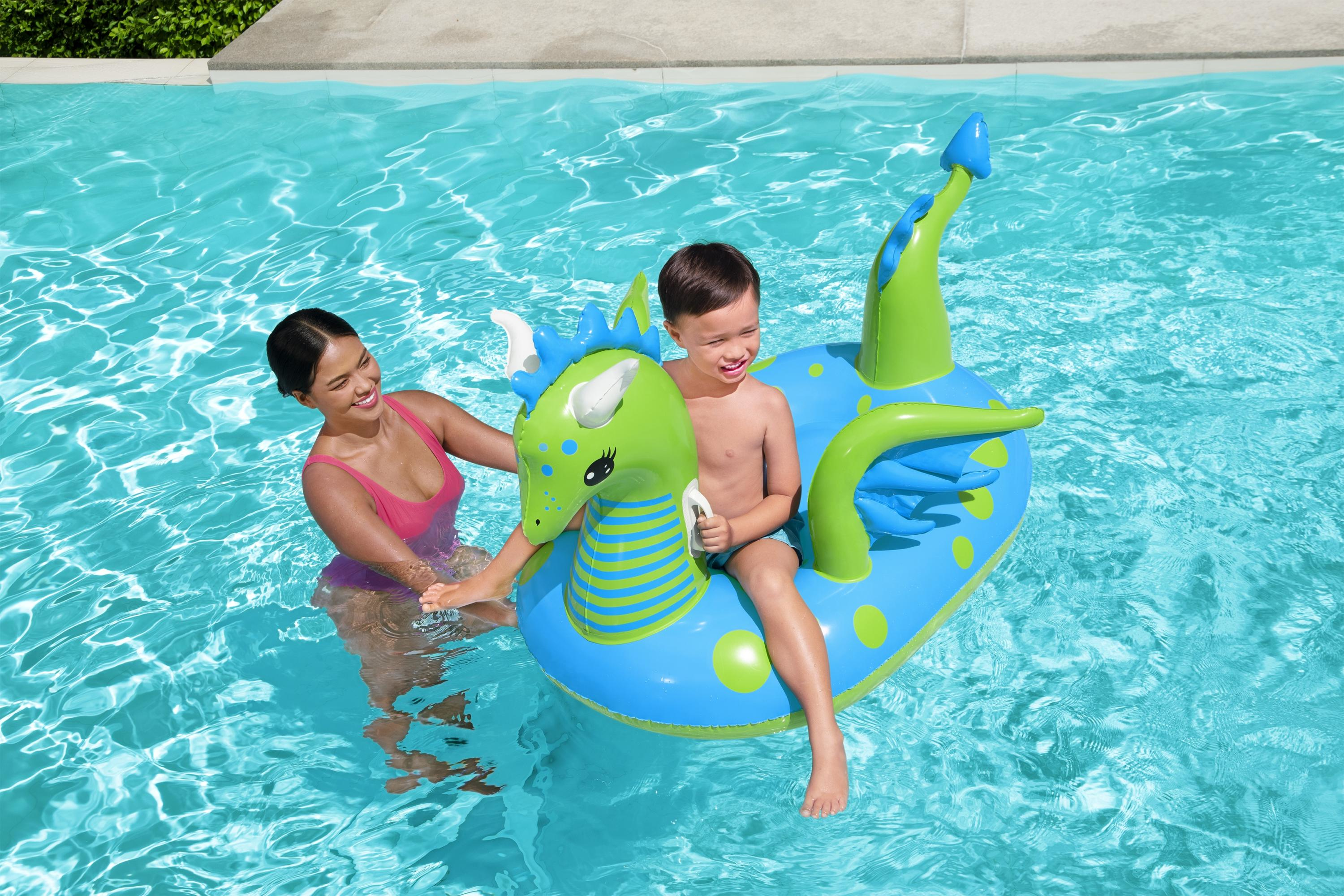 Una donna e un bambino in piscina. Il bambino è su un galleggiante a forma di drago. La donna lo aiuta.