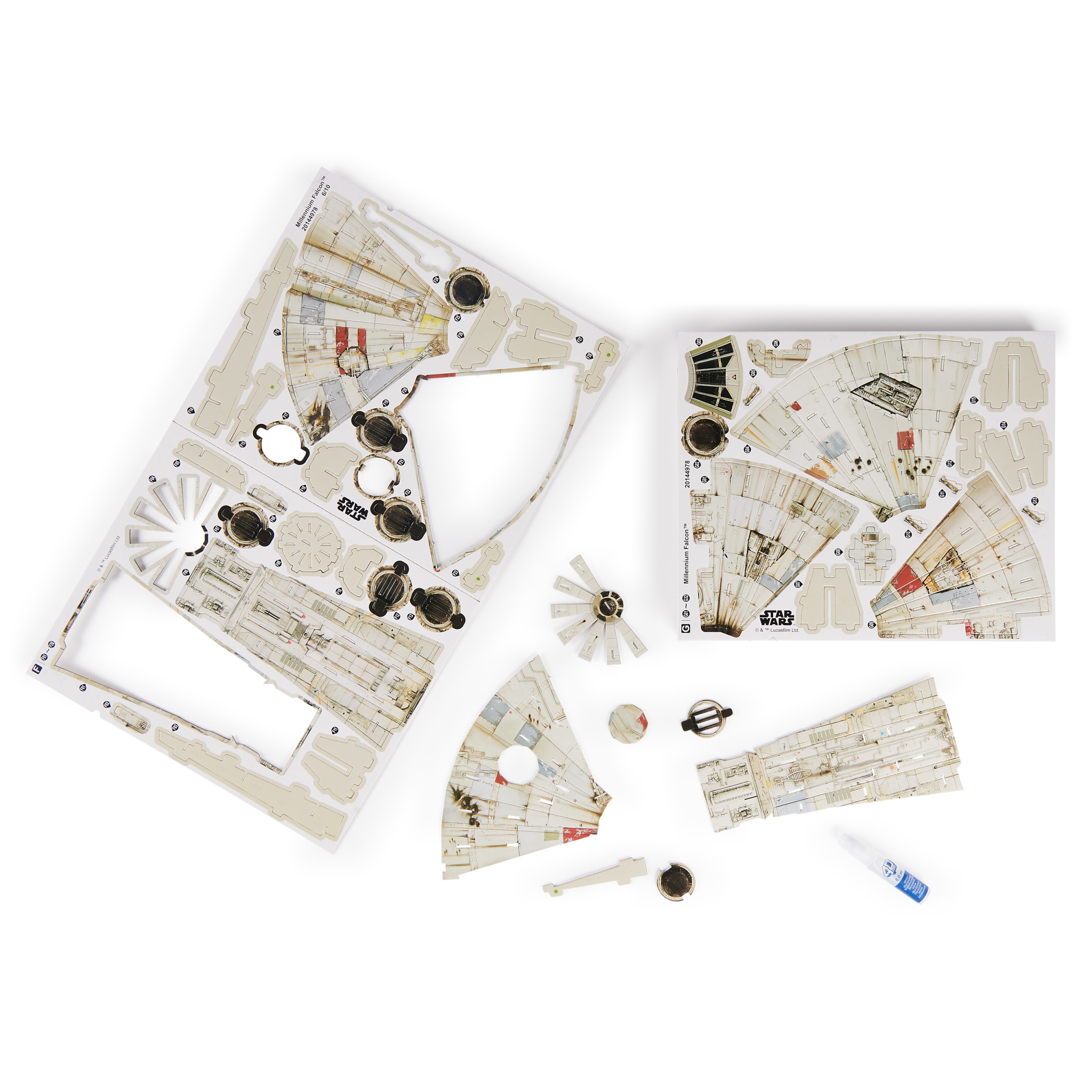 Elementy modelu Millennium Falcon na białym tle. Beżowe i białe kartonowe elementy, klej i konstrukcja w kształcie wachlarza.