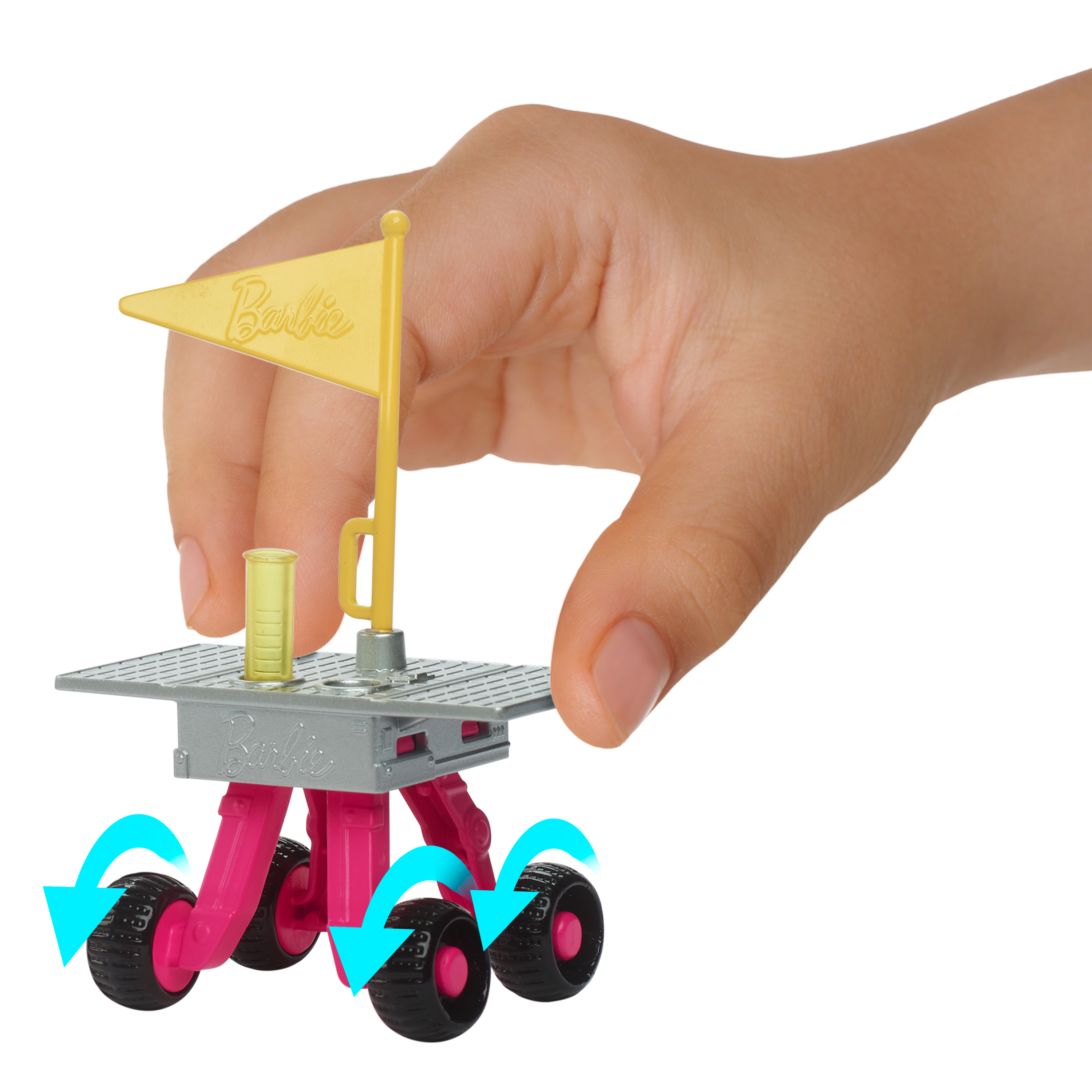 Ręka trzyma zabawkę. Jest różowa, szara i żółta z czarnymi kołami i flagą z napisem Barbie.