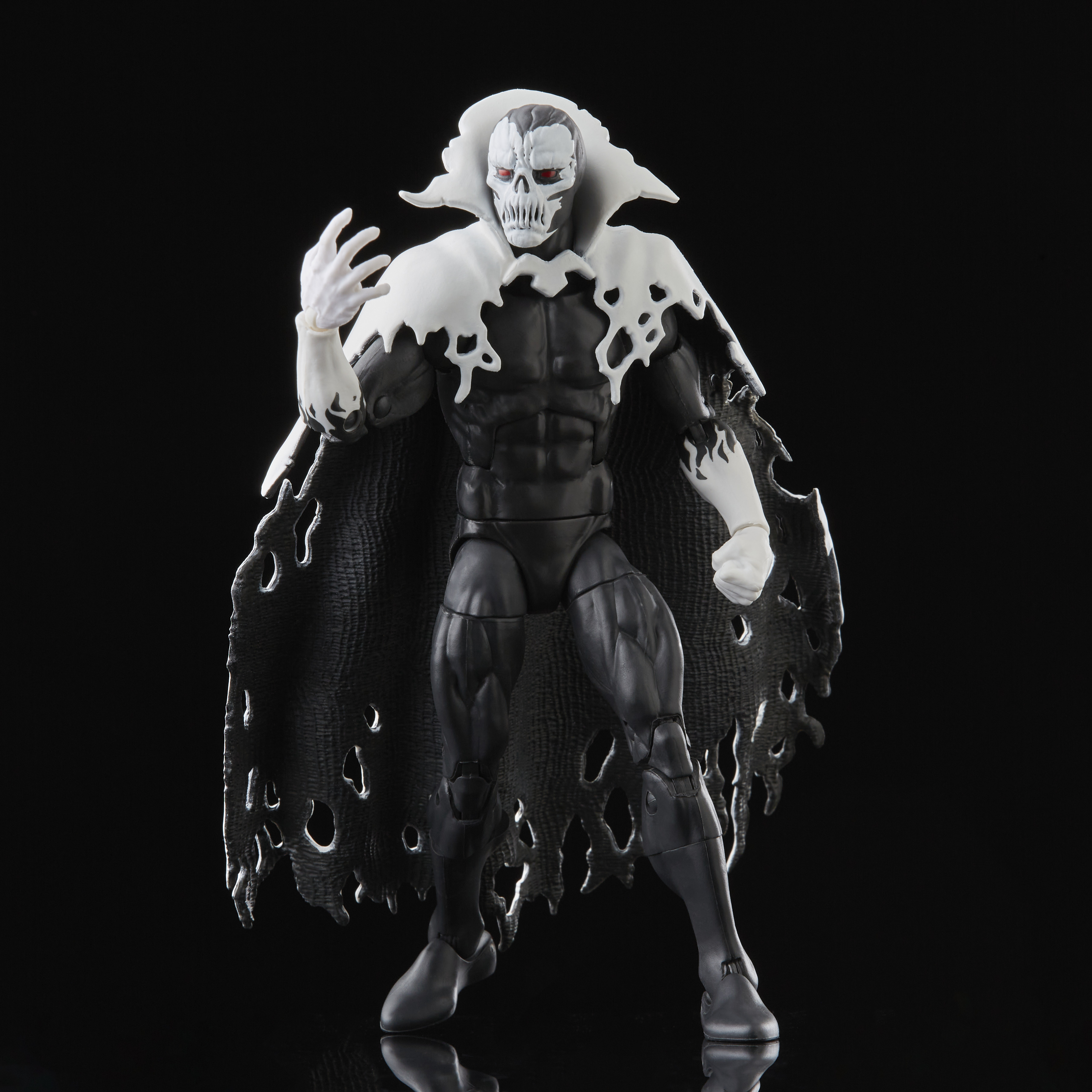 Action figure di un personaggio con volto a teschio, mantello bianco e completo nero. Occhi rossi. Sfondo nero.