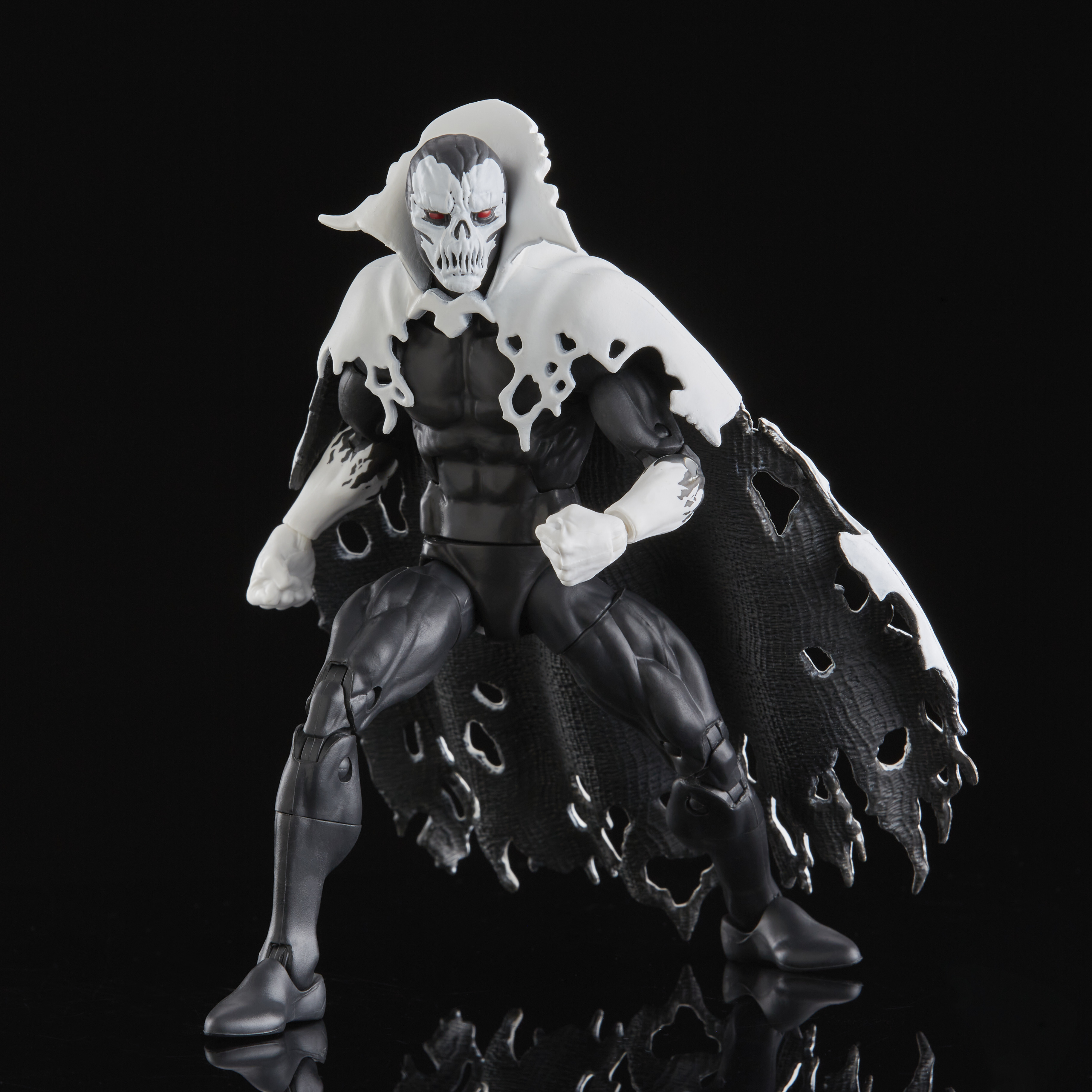 Action figure di un personaggio con un volto a teschio bianco, occhi rossi e un mantello bianco strappato, su sfondo nero.