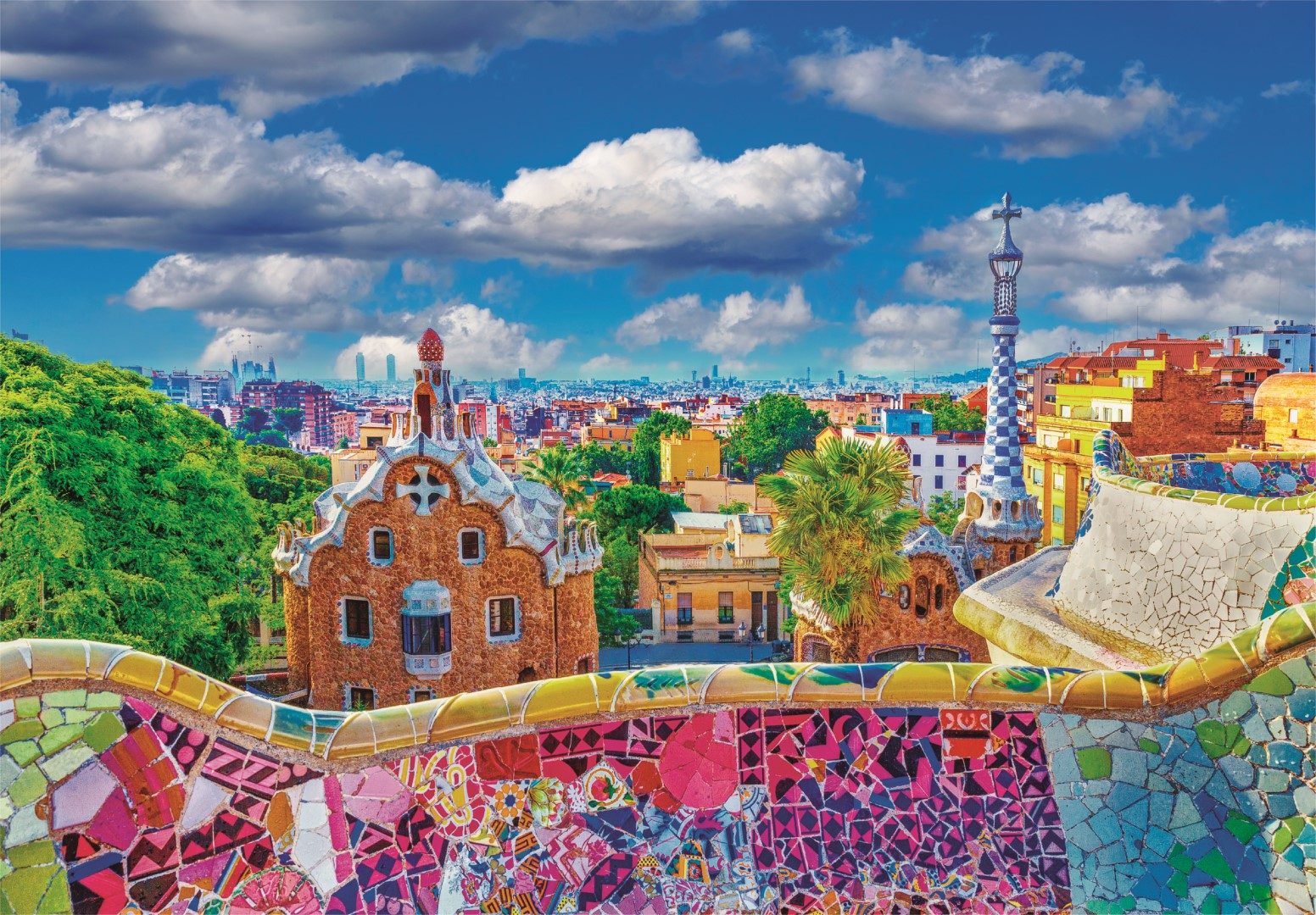 Vista del Park Güell a Barcellona con strutture a mosaico colorate ed edifici contro un cielo blu nuvoloso.