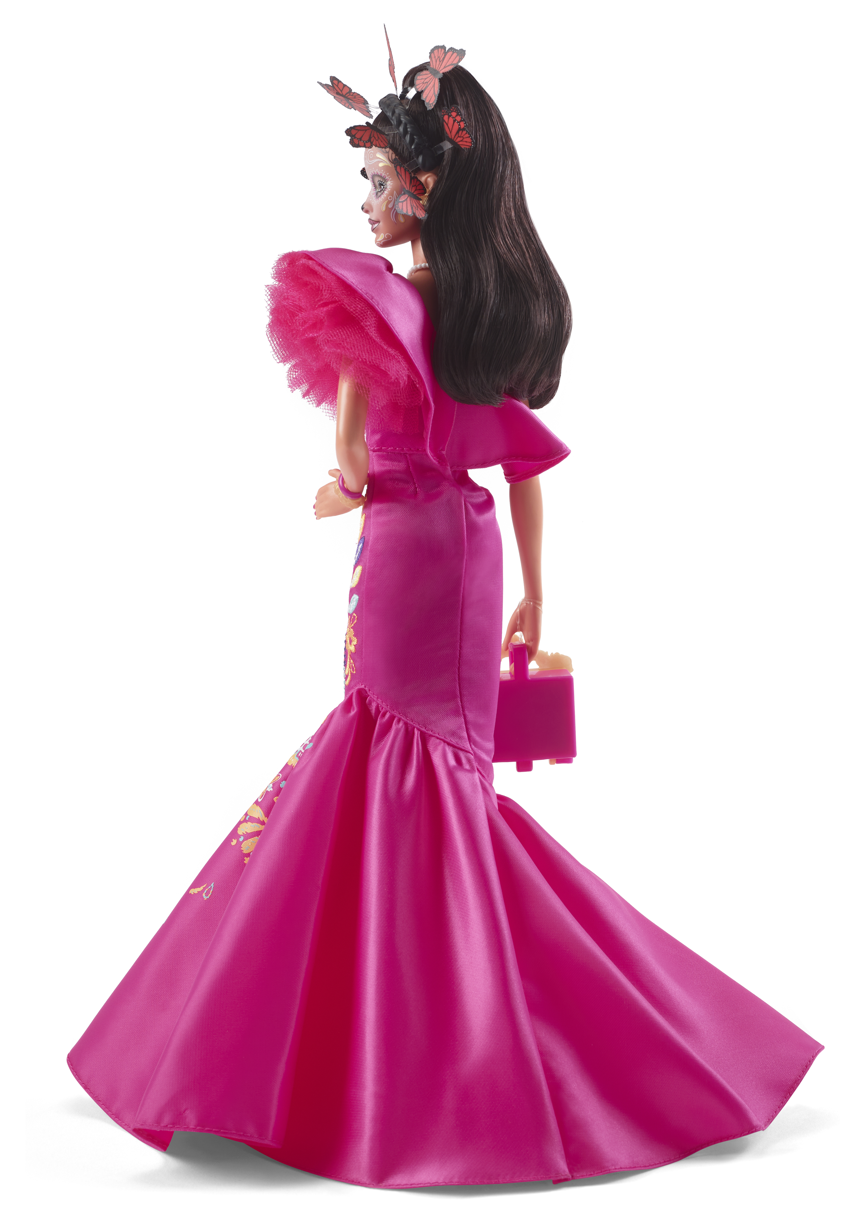 Puppe in pinkem Kleid mit Schmetterlingsdekorationen auf Kopf und Gesicht, hält eine pinke Handtasche.
