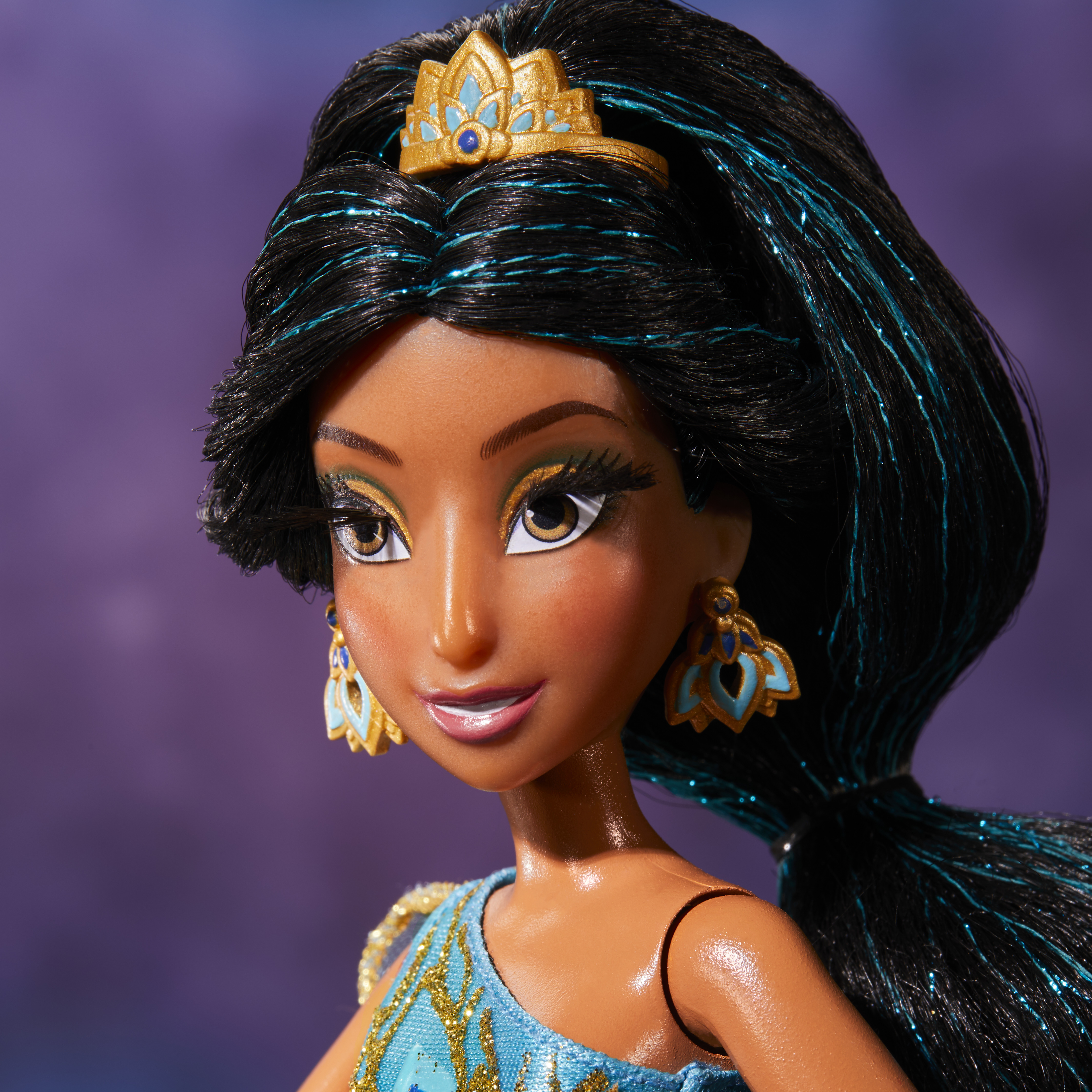Eine Jasmine-Puppe mit schwarzem Haar, goldener Krone und blauem Kleid. Lila Hintergrund.