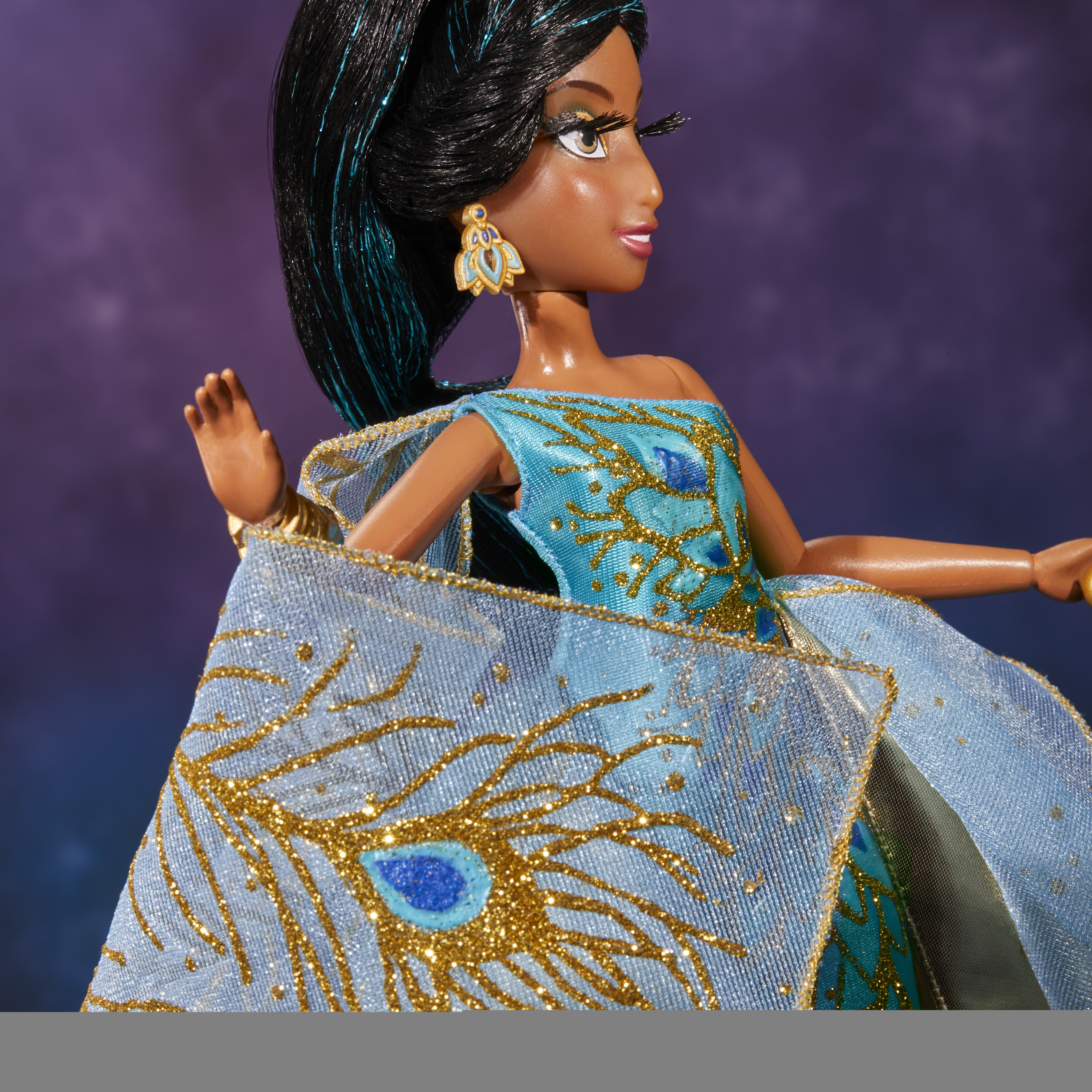 Eine Jasmin-Puppe in einem blauen Kleid mit goldenen Akzenten. Sie hat schwarzes Haar mit blauen Highlights und goldene Ohrringe.