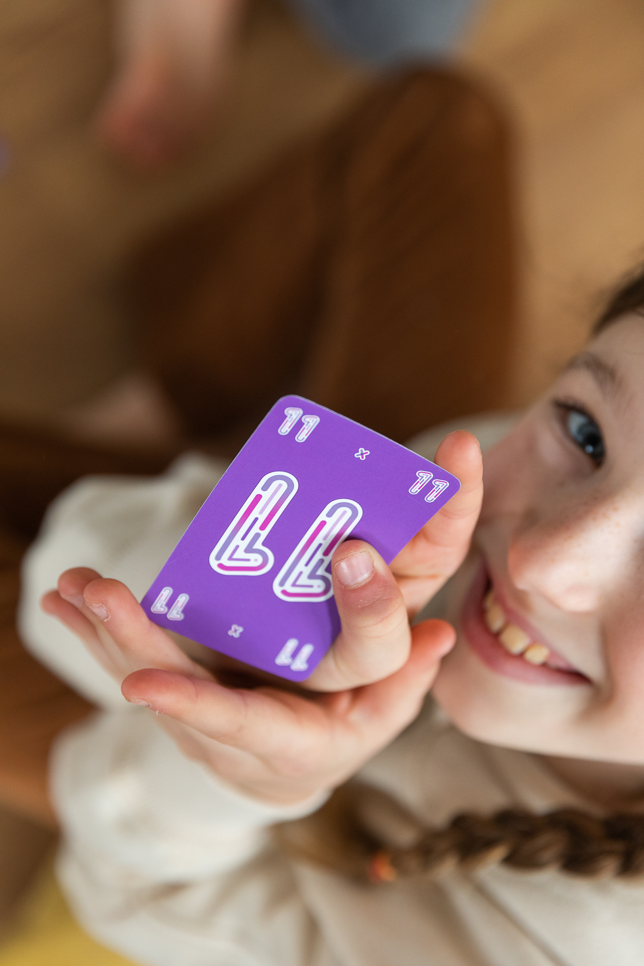 Ein Mädchen hält eine lila Karte mit '11'. Sie lächelt in die Kamera. Der Hintergrund ist unscharf.