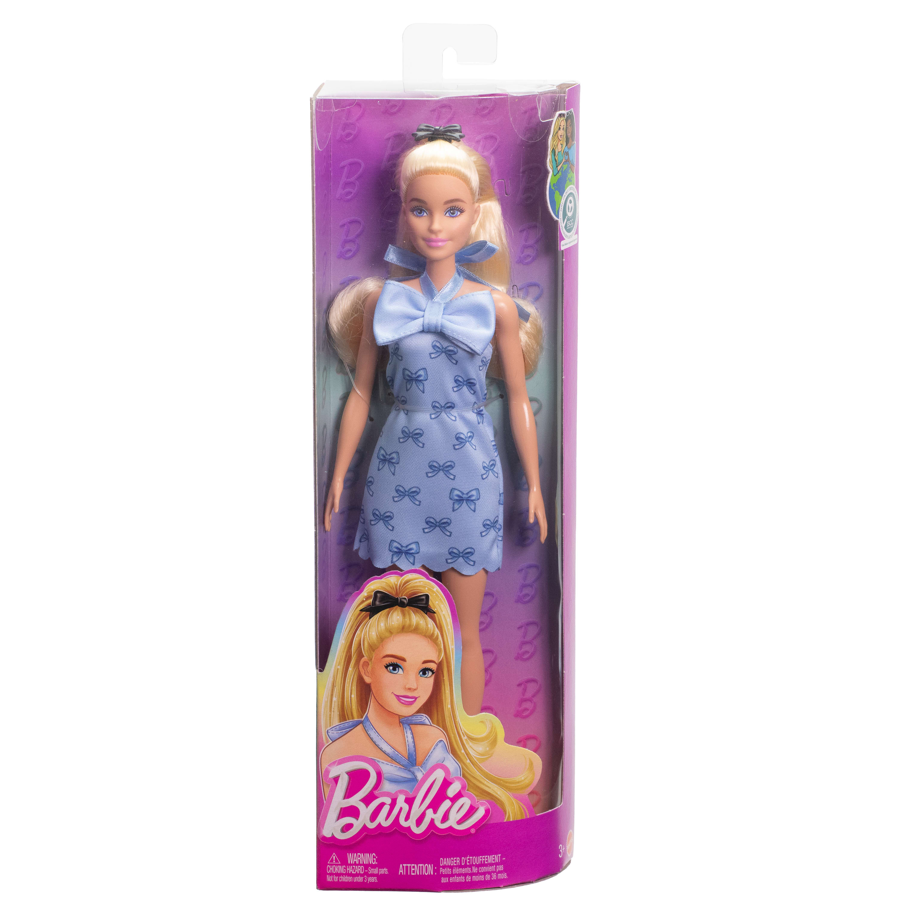 Barbie-Puppe in Verpackung. Sie hat blondes Haar, ein blaues Kleid mit Schleifen und eine schwarze Schleife im Haar.