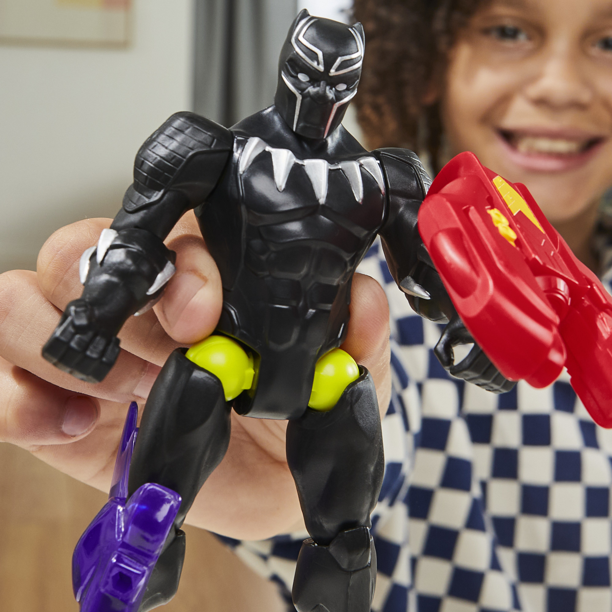 Un niño sostiene una figura de acción de Black Panther. Es negra con detalles plateados y un escudo rojo. El niño sonríe.