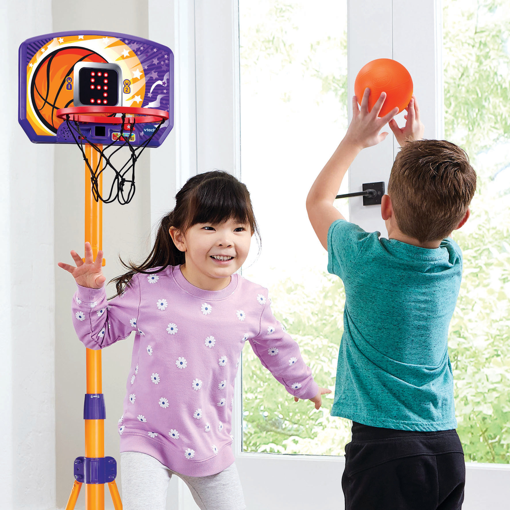 Due bambini giocano a basket. Uno lancia una palla arancione verso il canestro. L'altro bambino sorride e gesticola.