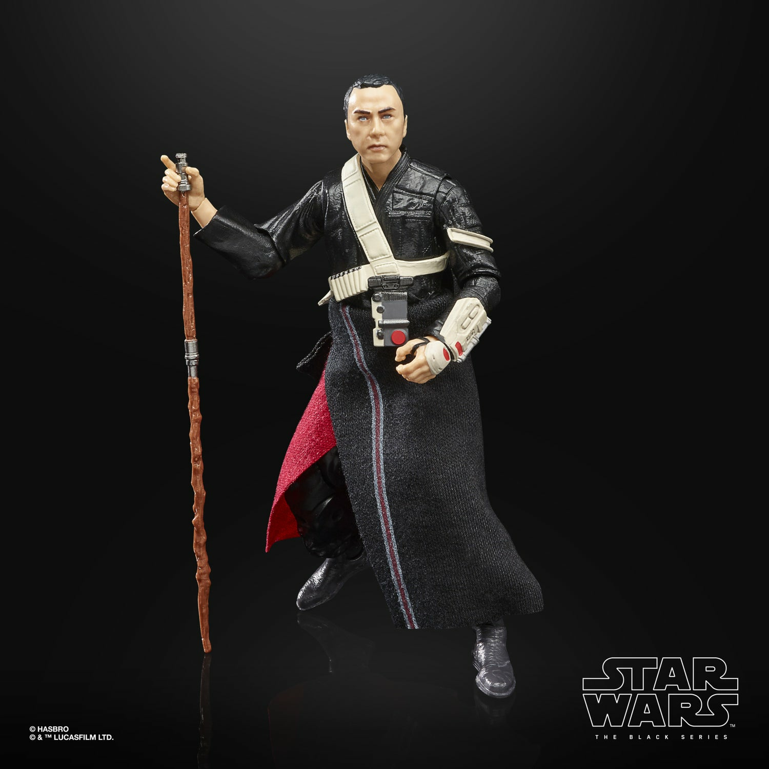 Una figura de Star Wars de un hombre vestido de negro con un bastón. Lleva una bandolera blanca y tiene una expresión seria.