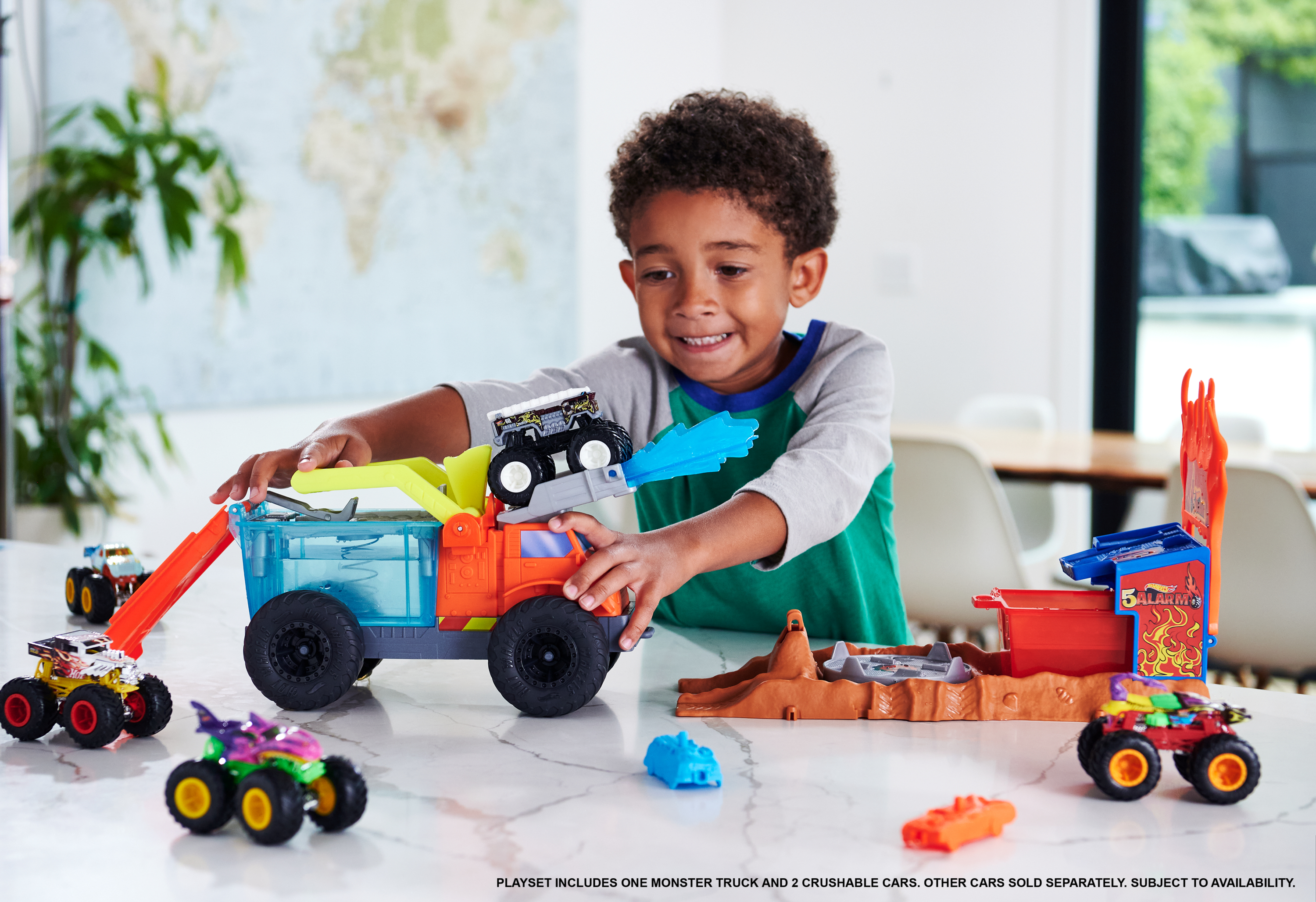 Dziecko bawi się zestawem zabawek z potwornym wozem. Zawiera ciężarówkę, samochody i konstrukcję do zabawy.