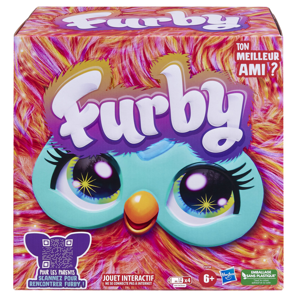 Pudełko z zabawką Furby. Ma twarz Furby z dużymi oczami i dziobem. Tło to kolorowe futro.