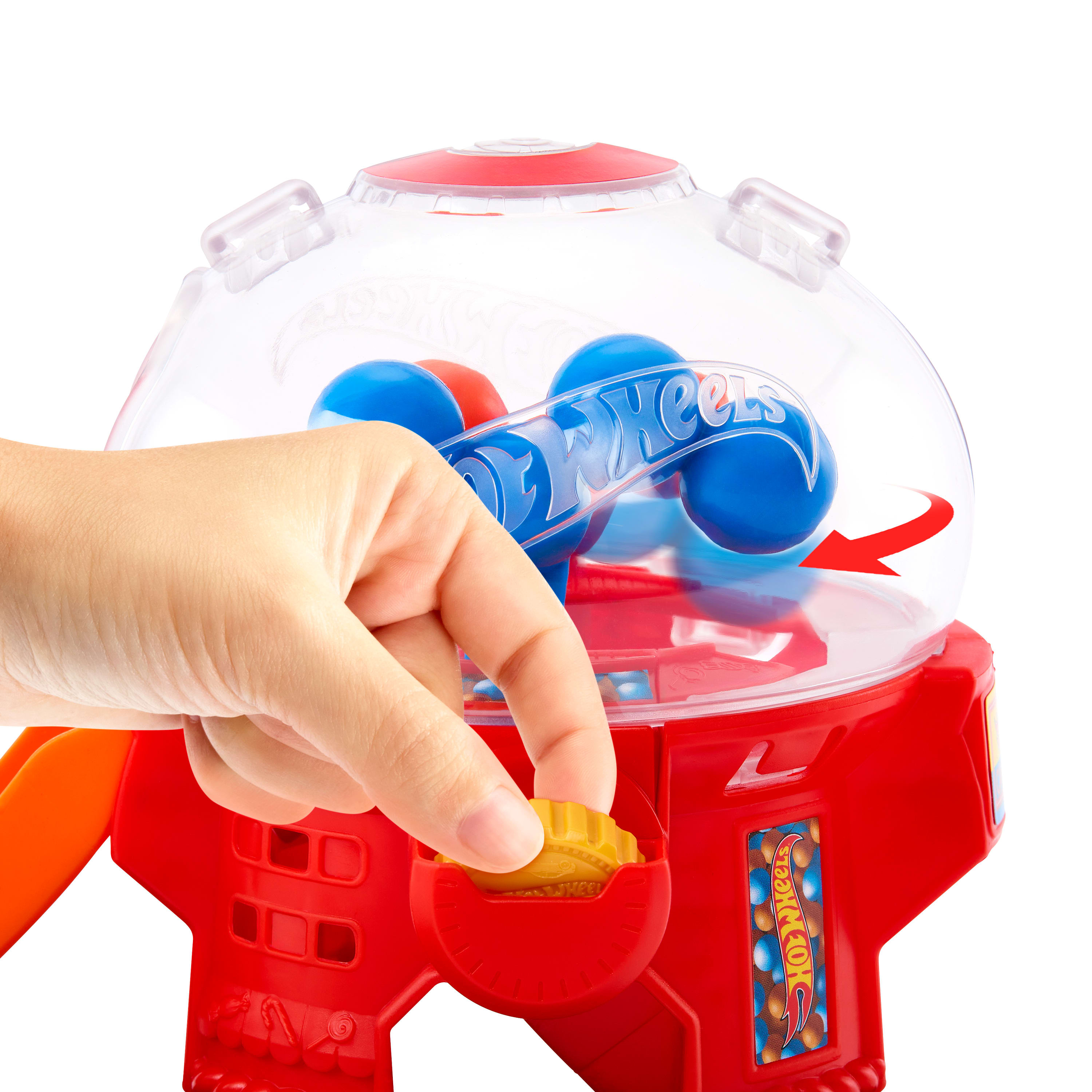 Ręka wkłada monetę do czerwonego automatu do gumy Hot Wheels. W środku są niebieskie i czerwone kulki.