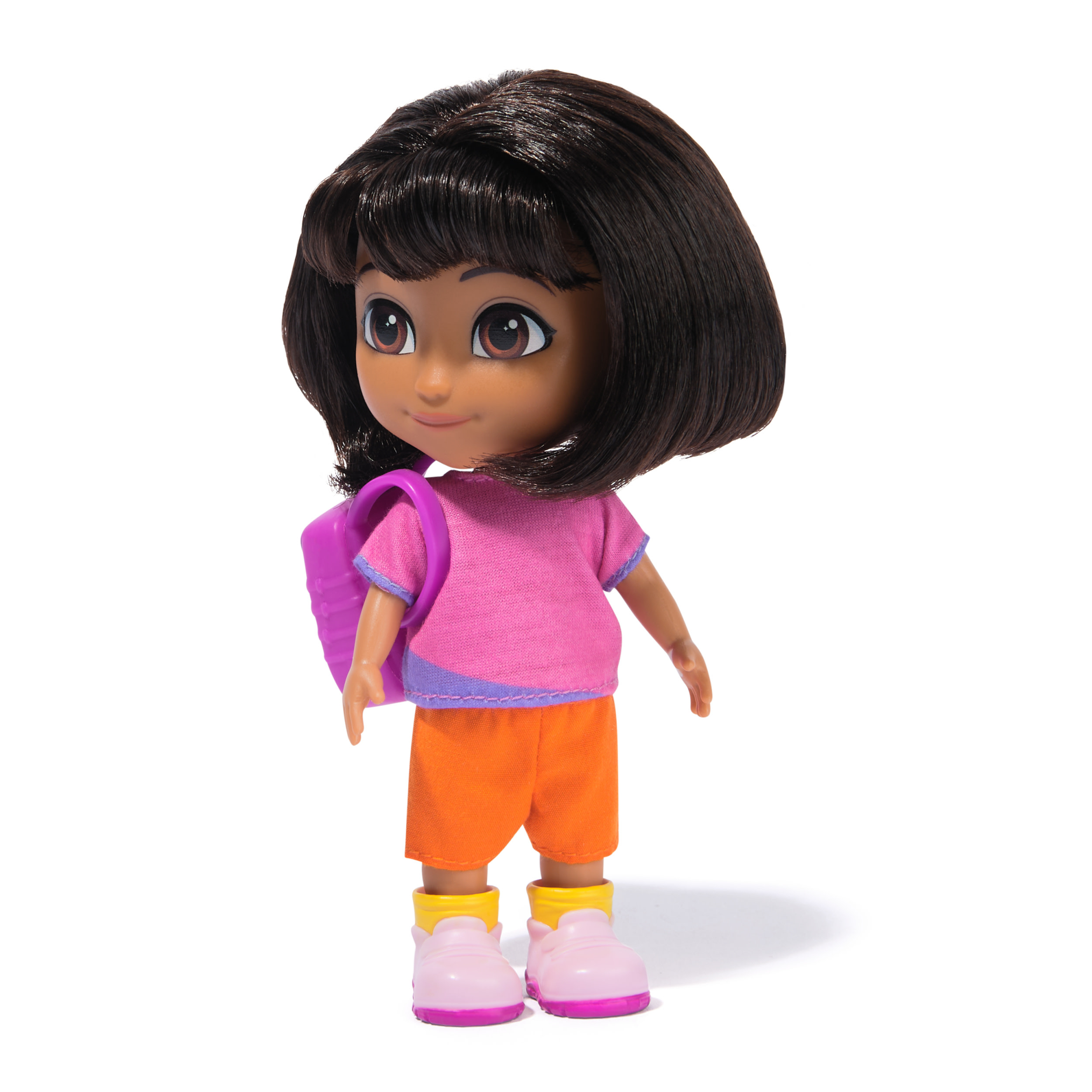 Una muñeca Dora, con camisa rosa, pantalones cortos naranjas, mochila morada y zapatos rosas con detalles amarillos, sobre fondo blanco.