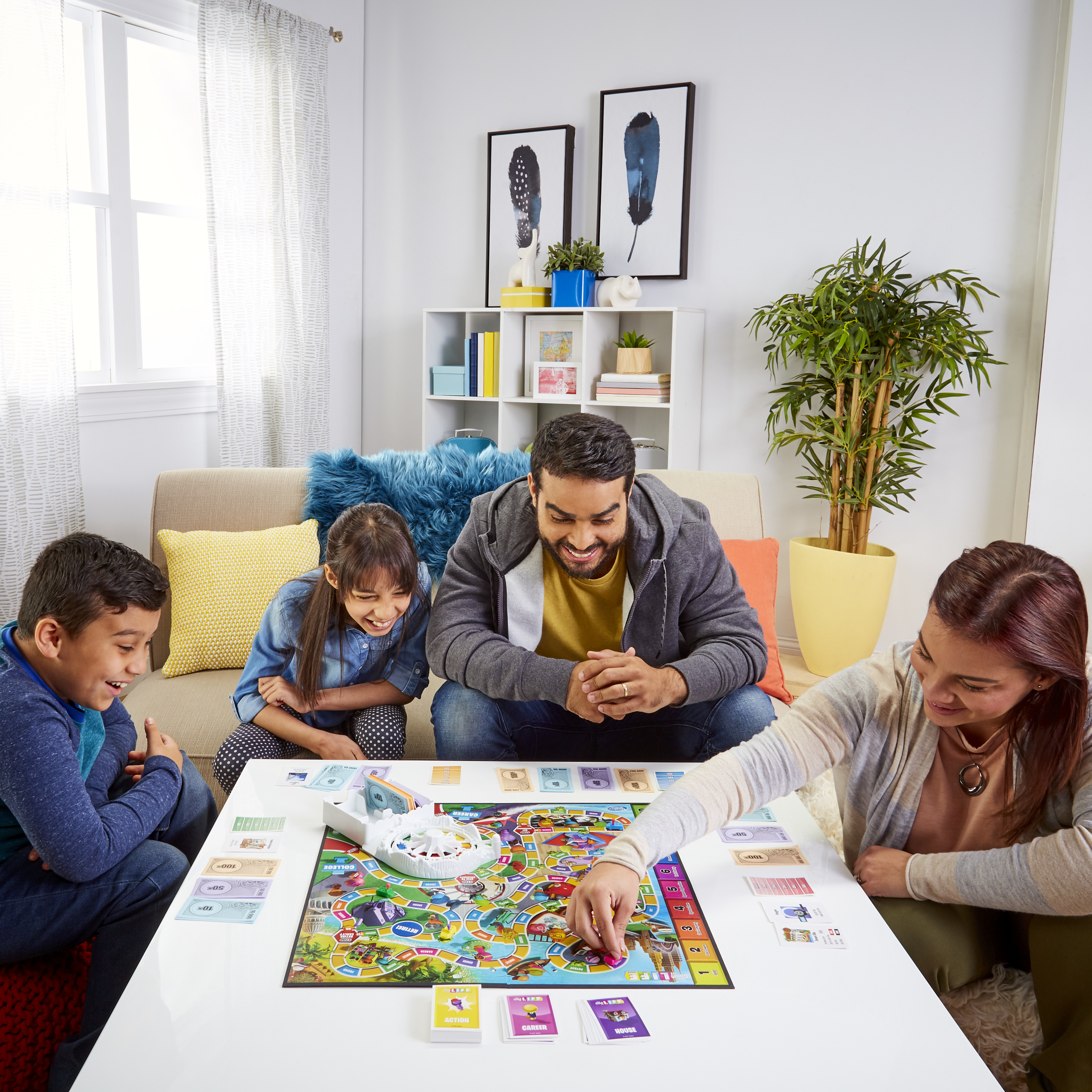 Een gezin speelt een bordspel. Een tafel bevat het spel, geld en kaarten. Mensen glimlachen en communiceren.