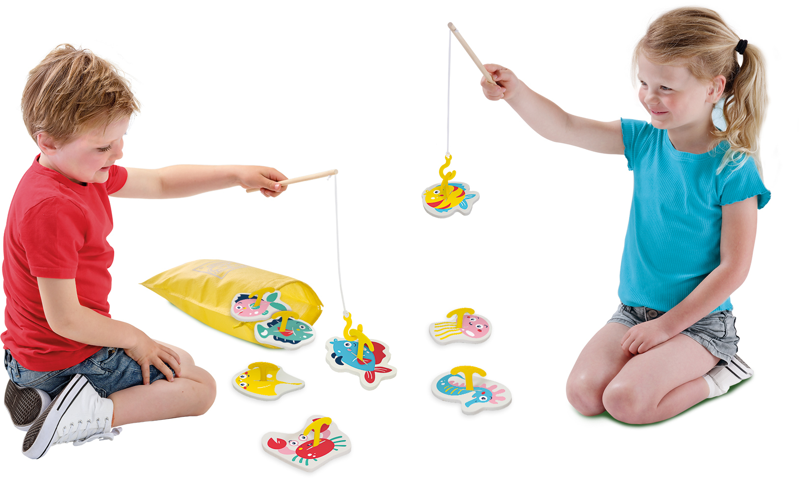 Due bambini giocano a un gioco di pesca con colorati giocattoli a forma di pesce. Un bambino è seduto, la bambina è in ginocchio. Un sacco giallo contiene più pesci.