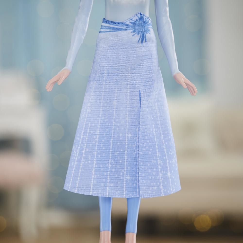 Eine Puppe trägt ein hellblaues Kleid mit Schlitz und passenden Leggings. Das Kleid hat einen gemusterten Rock und einen dekorativen Gürtel.