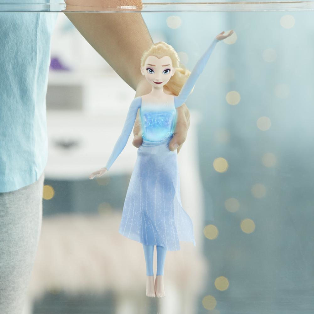 Eine Person hält eine Elsa-Puppe unter Wasser. Die Puppe trägt ein hellblaues Kleid. Der Hintergrund ist mit Bokeh verschwommen.