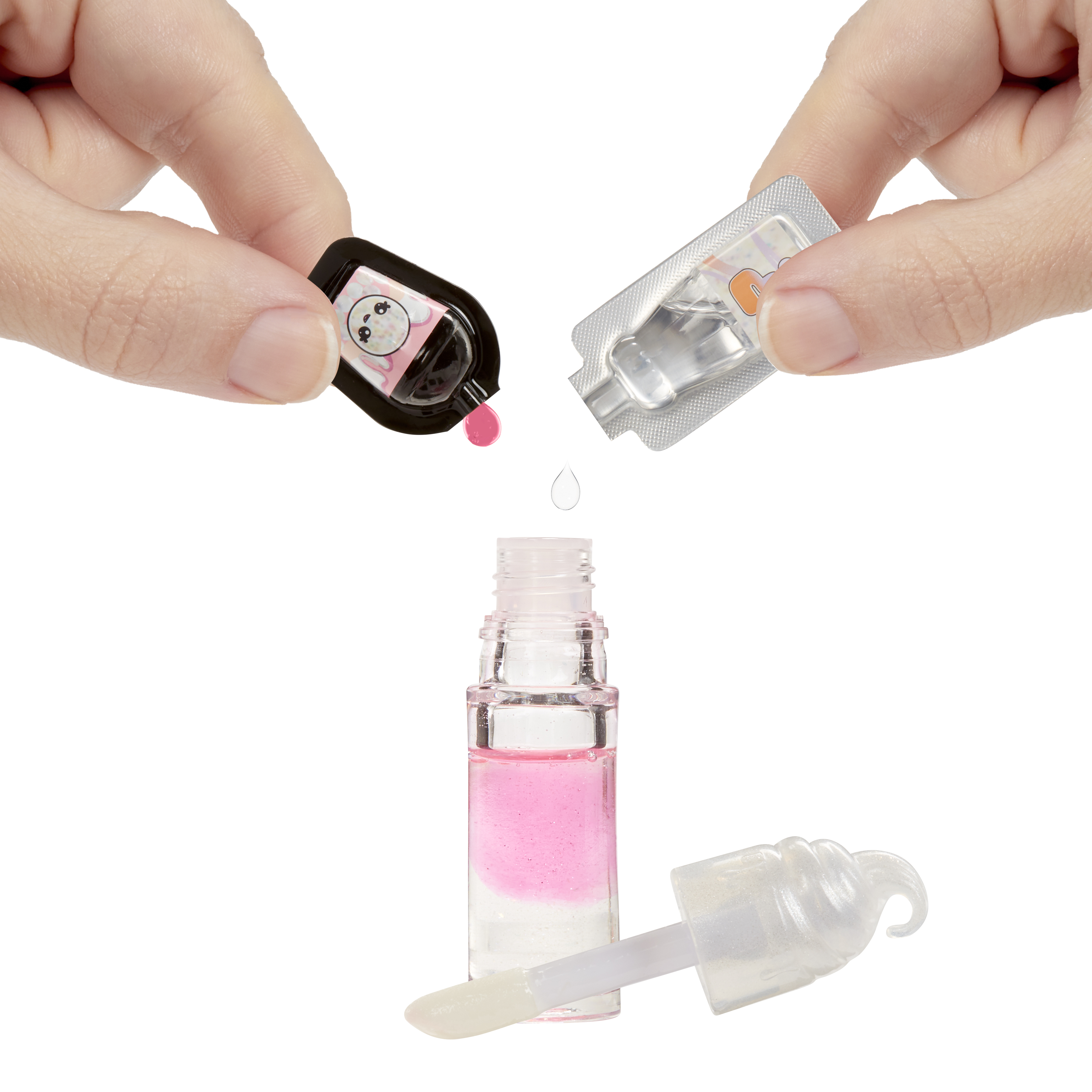 Dłonie trzymają pojemniki wlewające płyn do butelki błyszczyka. Widoczne są różowe i przezroczyste płyny.