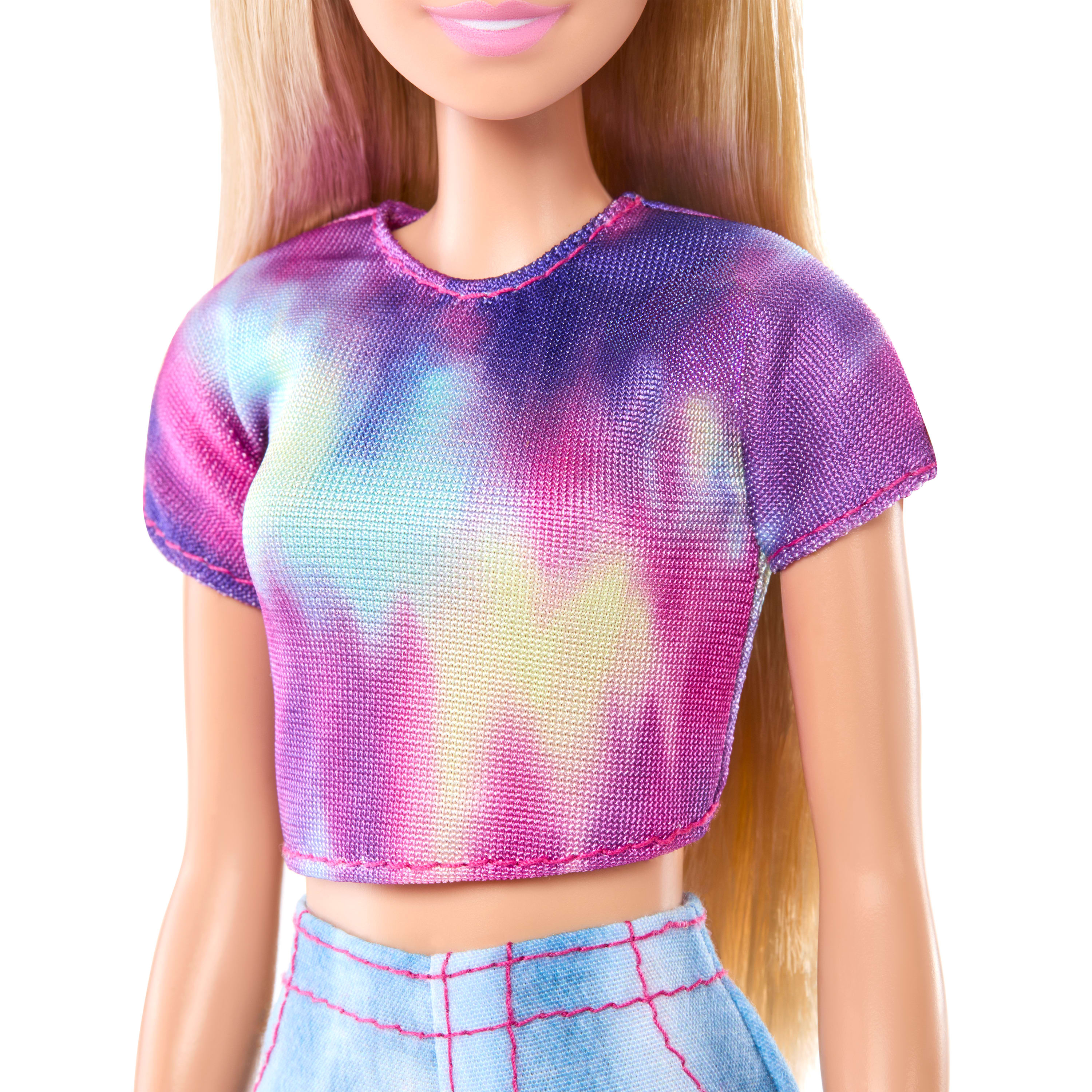 Eine Barbie-Puppe mit blonden Haaren, einem Batik-Shirt und einem karierten Rock wird gezeigt. Der Hintergrund ist weiß.