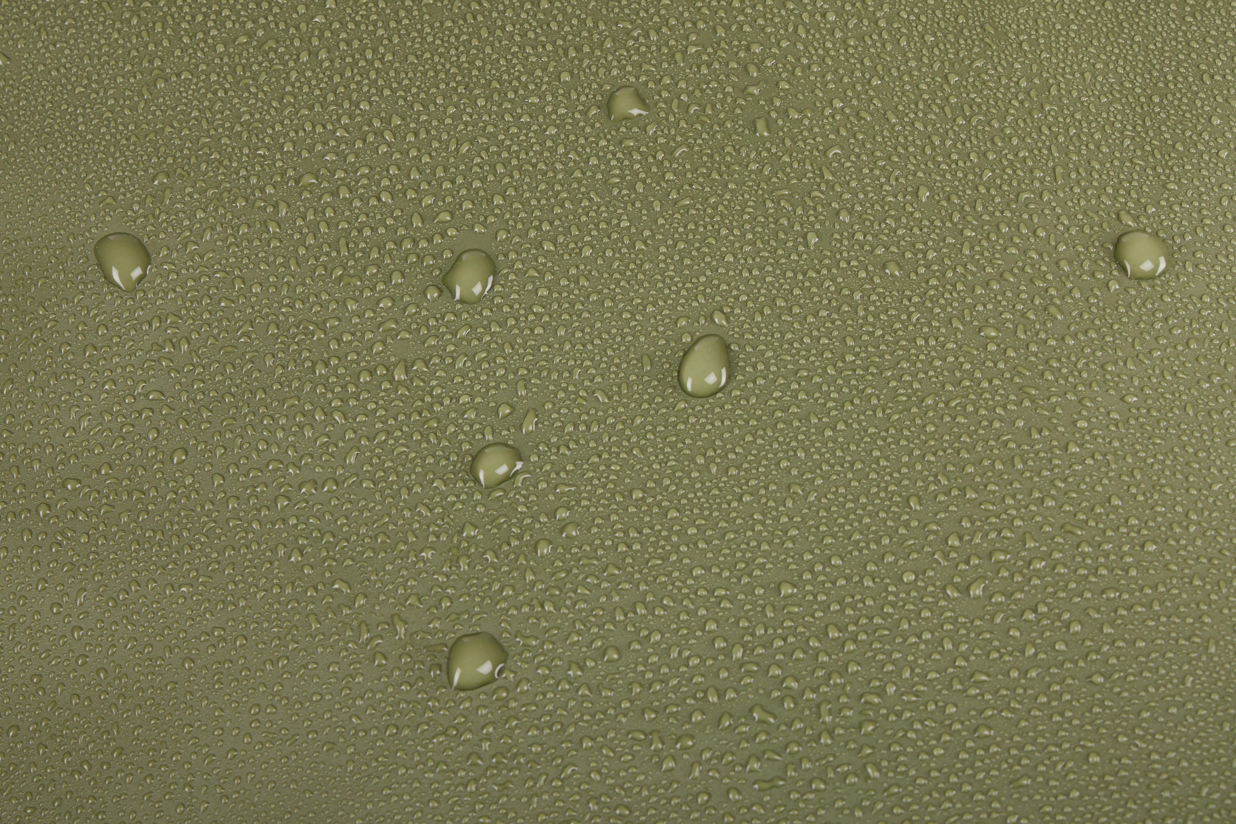 Zbliżenie zielonej powierzchni pokrytej kroplami wody o różnych rozmiarach. Krople odbijają światło.