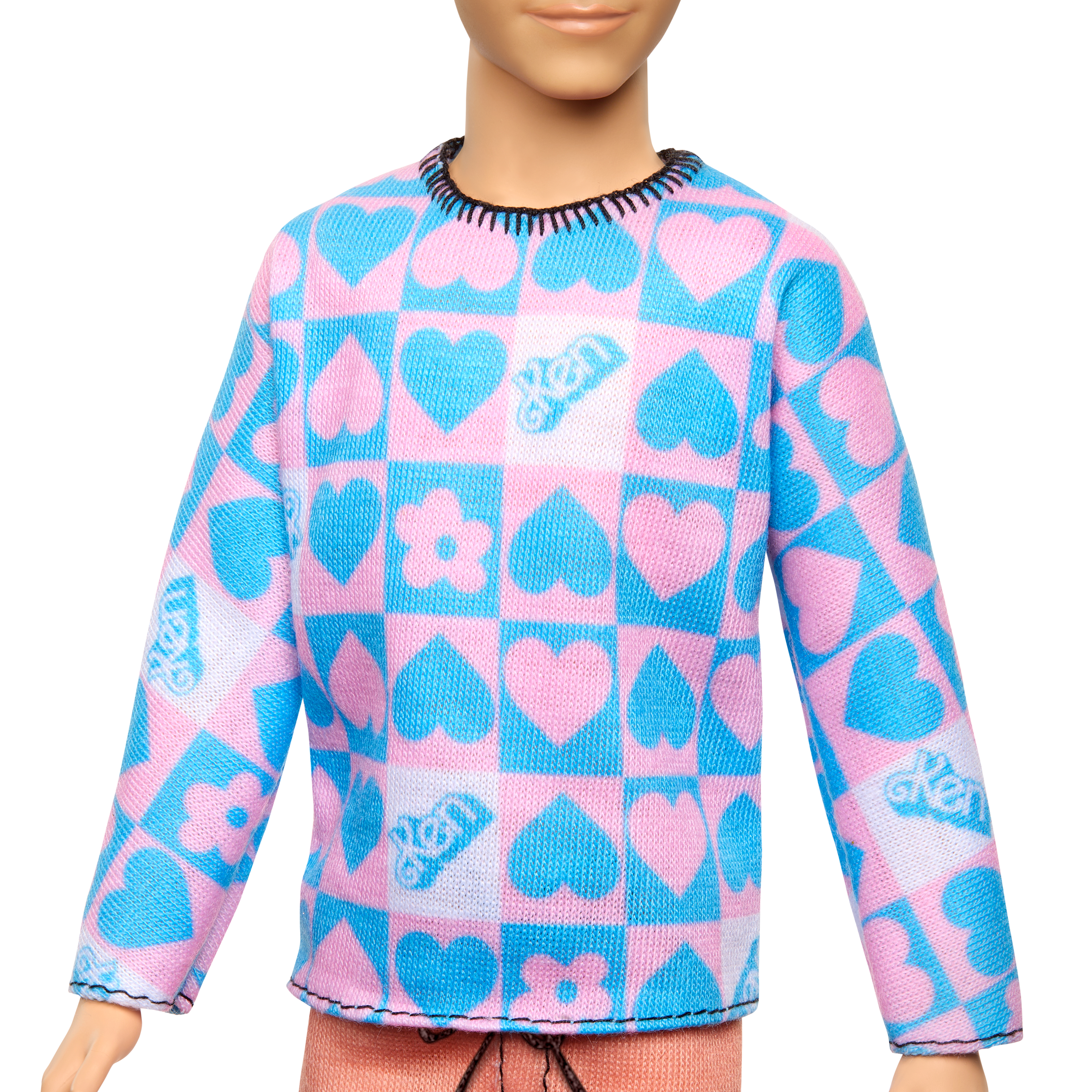 Eine Puppe trägt einen rosa-blauen Pullover mit Herz- und Blumenmustern. Der Pullover hat einen schwarzen Besatz.