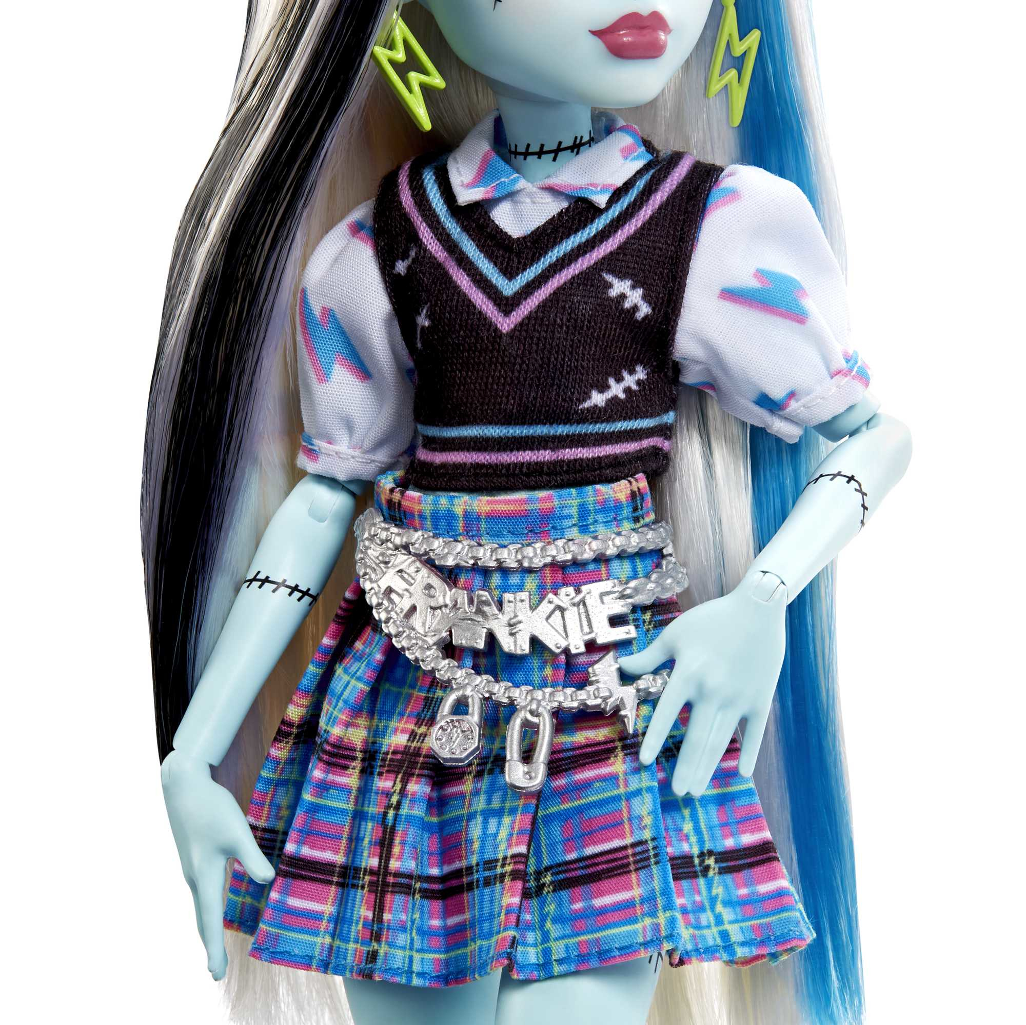 Eine Puppe mit blauer Haut, schwarz-weißem Haar. Trägt einen karierten Rock, einen schwarzen Pullover und silberne Accessoires. Die Puppe hat Stiche.