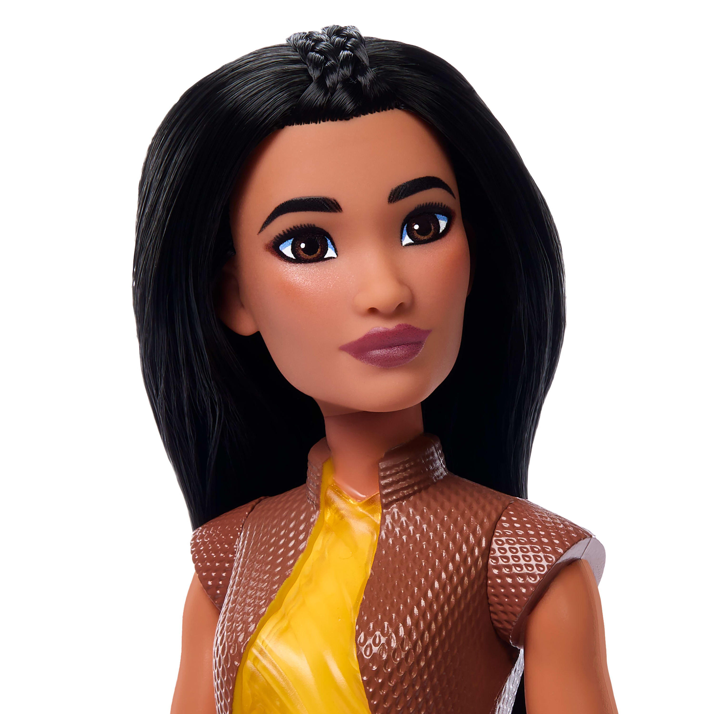 Lalka z ciemnymi włosami i brązowymi oczami. Nosi brązową kamizelkę na żółtej koszuli. Białe tło.