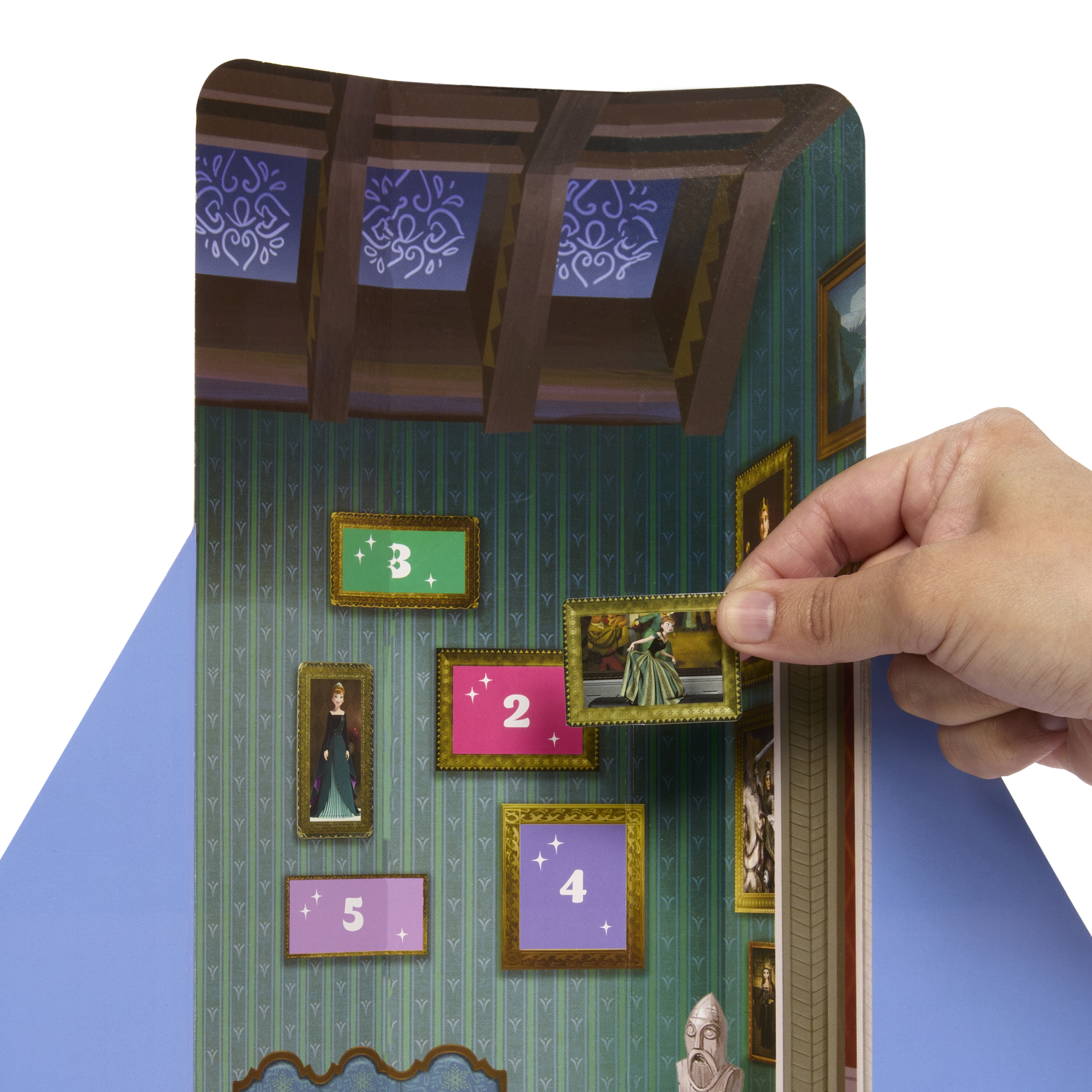 Ręka umieszcza obrazek na ścianie z innymi oprawionymi obrazami. Ściana jest turkusowa i ma numery na ramkach.