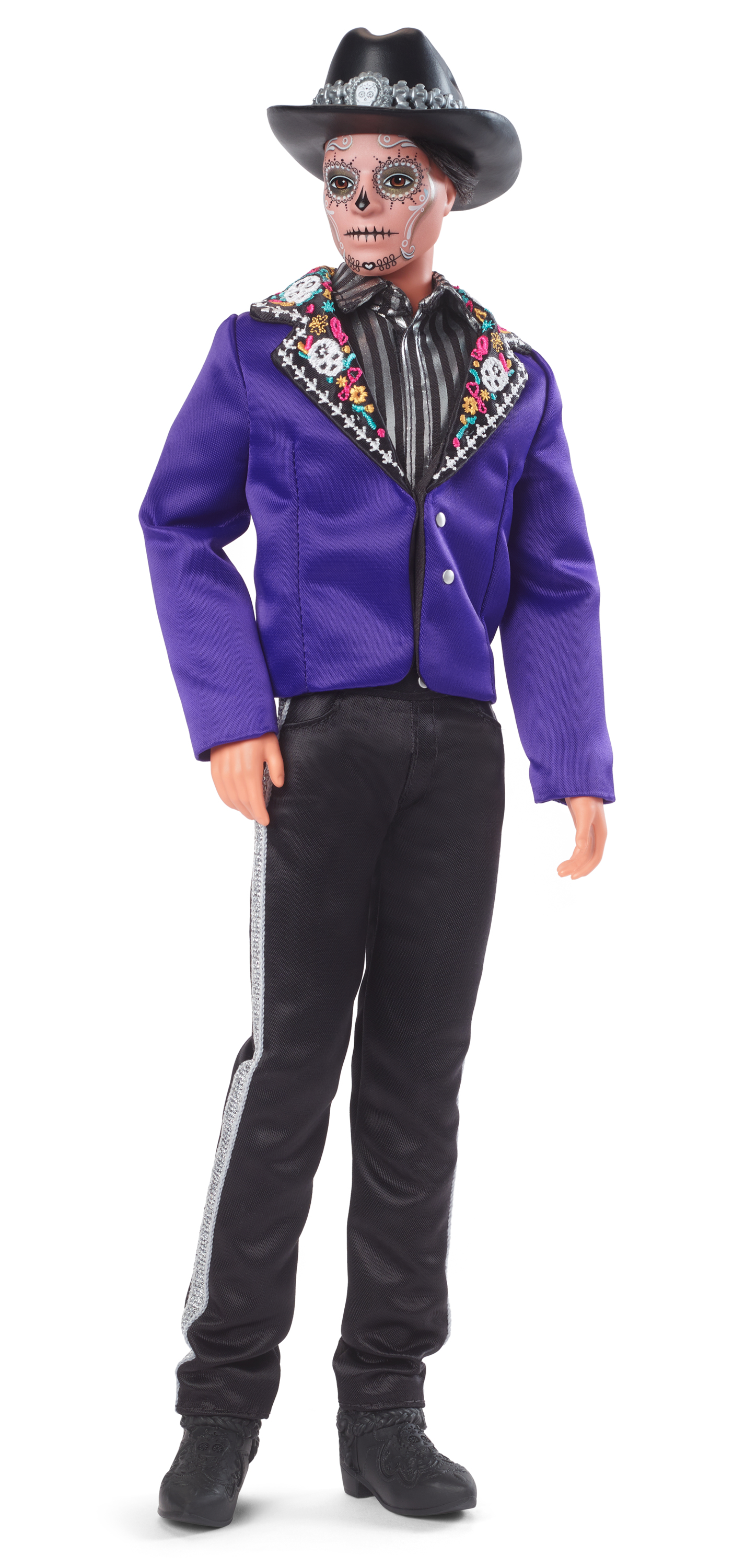 Lalka z makijażem cukrowej czaszki i czarnym kapeluszem. Nosi fioletową kurtkę, czarne spodnie ze srebrnymi paskami i czarne buty.