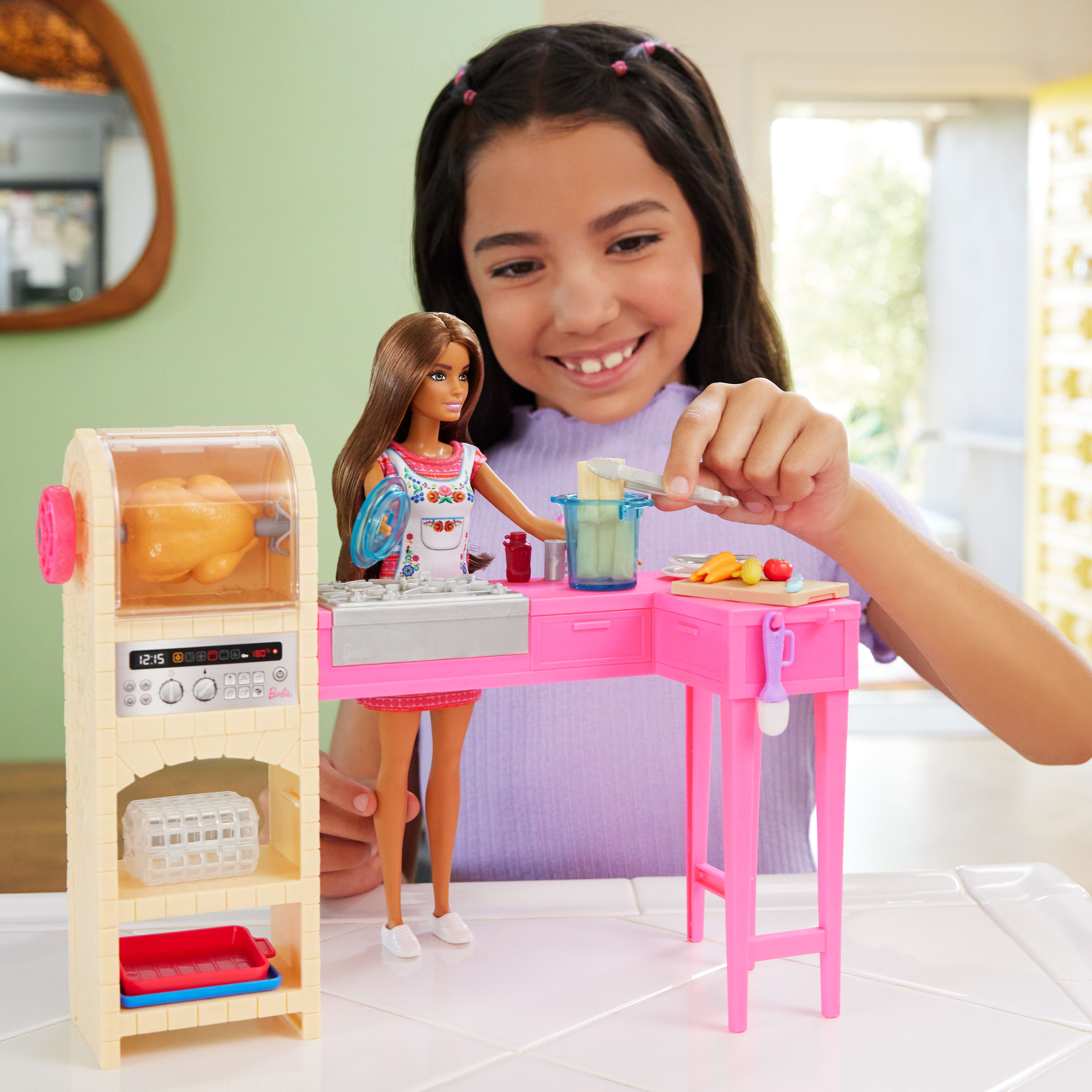 Ein Mädchen spielt mit einem Barbie-Küchenset, einschließlich einer Puppe und einem Spielzeugofen, Tisch und Lebensmitteln.