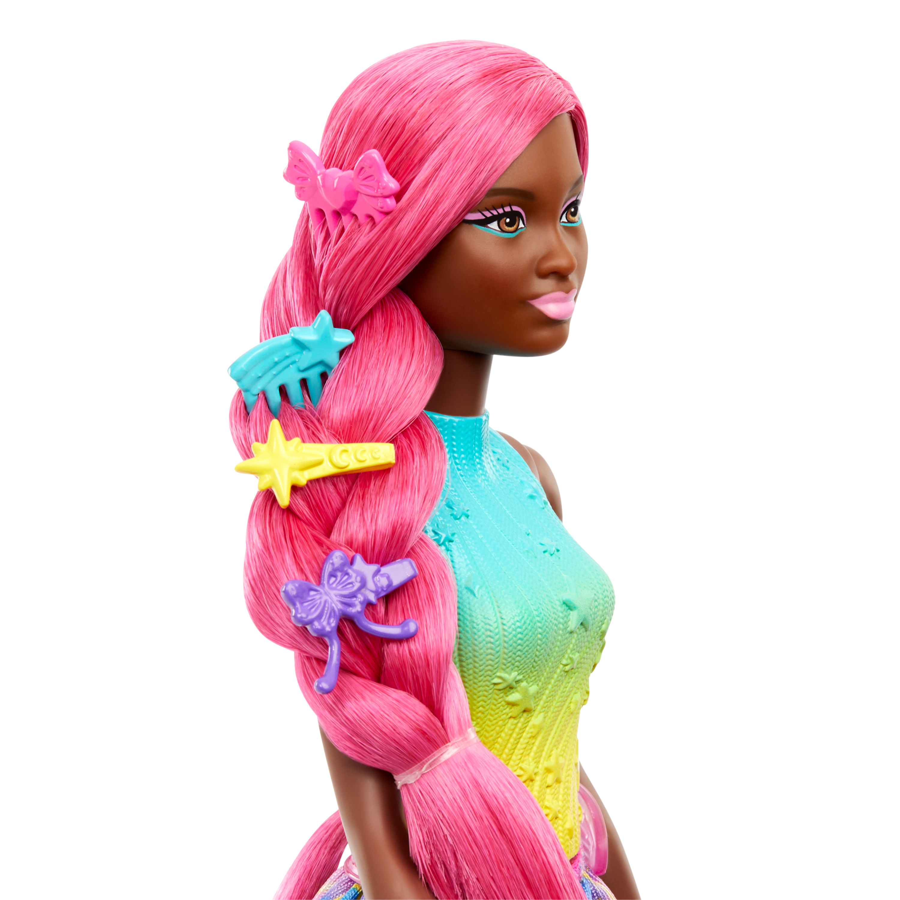 Eine Puppe mit pinkfarbenem Haar, verziert mit bunten Clips, trägt ein Regenbogen-Top und Make-up. Die Puppe hat dunkle Haut.