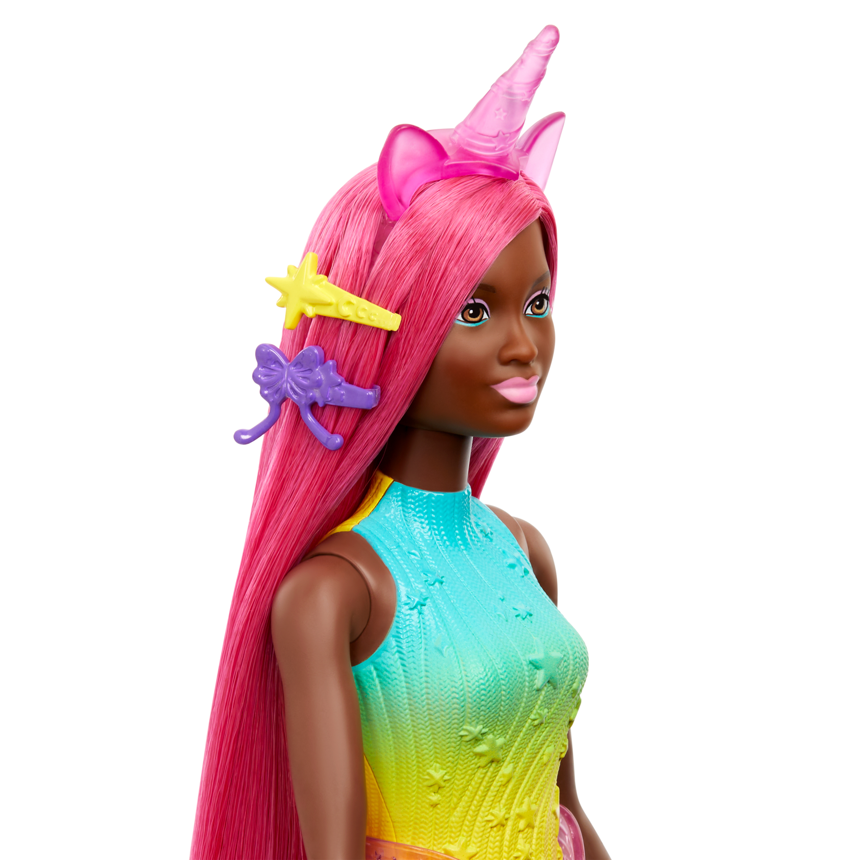 Puppe mit pinkfarbenem Haar, Einhornhorn und farbenfrohem Kleid. Zubehör sind gelbe Stern- und lila Schleifen-Haarspangen.