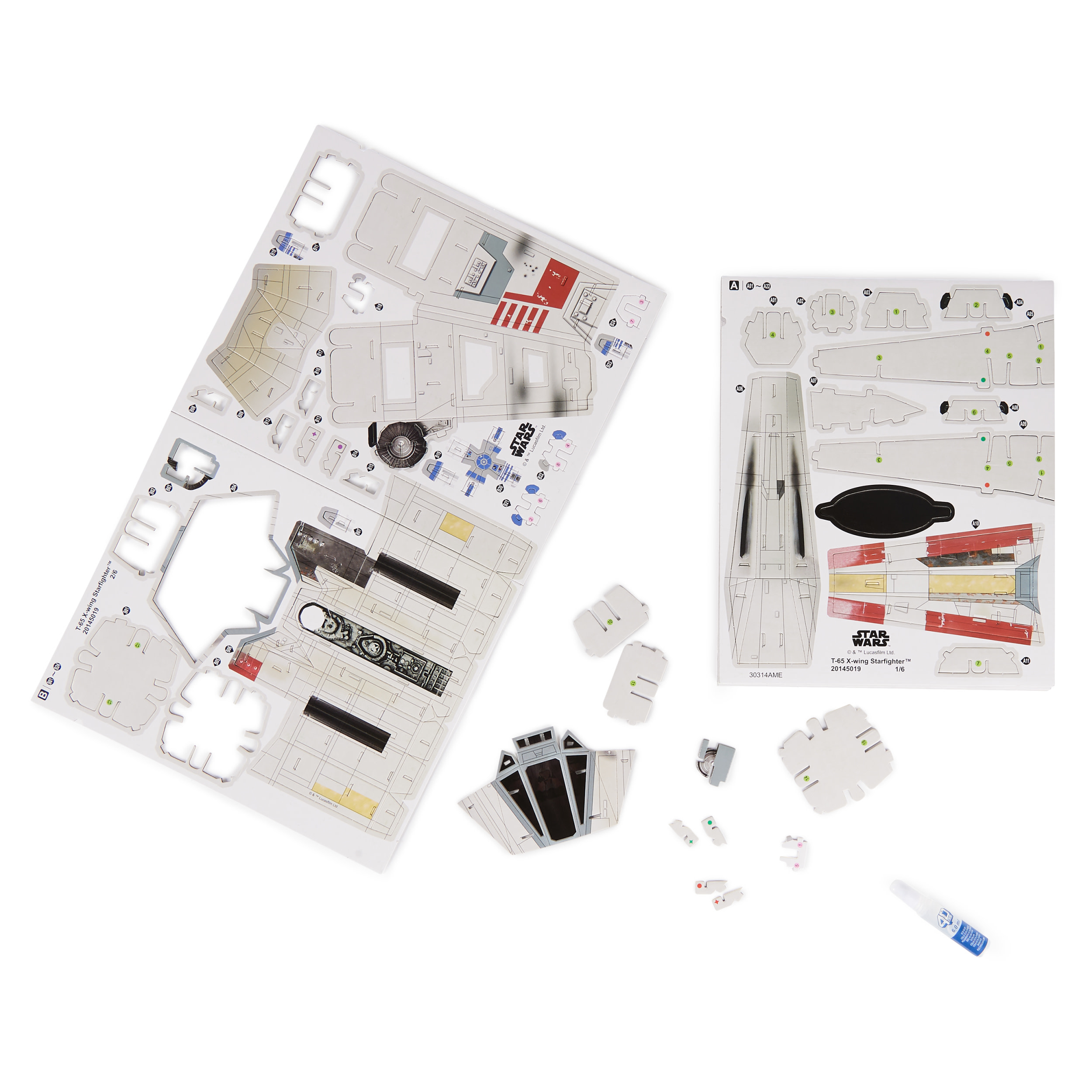 Zdemontowany model Star Wars X-wing z różnymi kartonowymi elementami, instrukcjami i klejem.