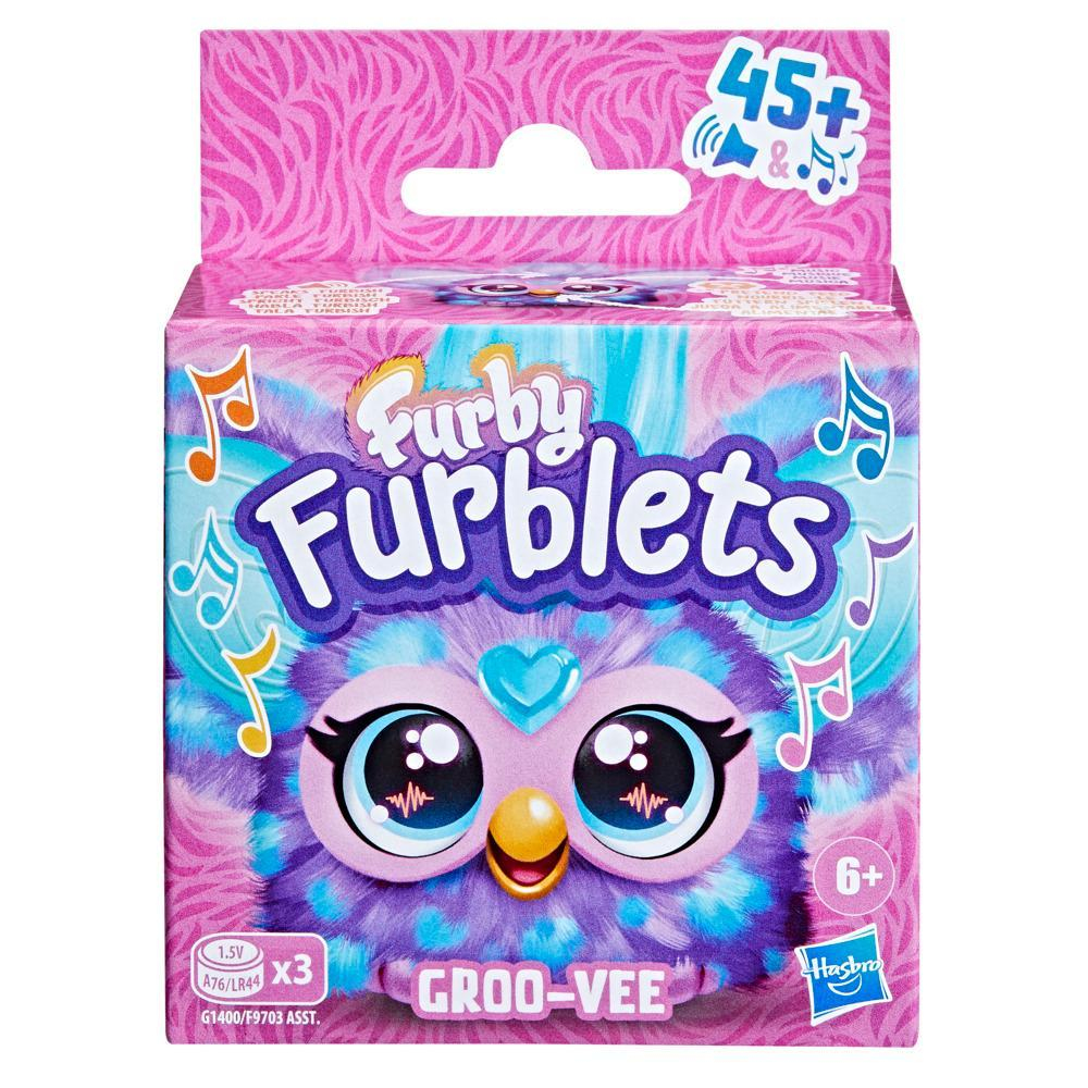 Una caja de Furby Furblets. Tiene una cara de Furby morada y azul con ojos grandes. La caja dice 'GROO-VEE' y 'Hasbro'.