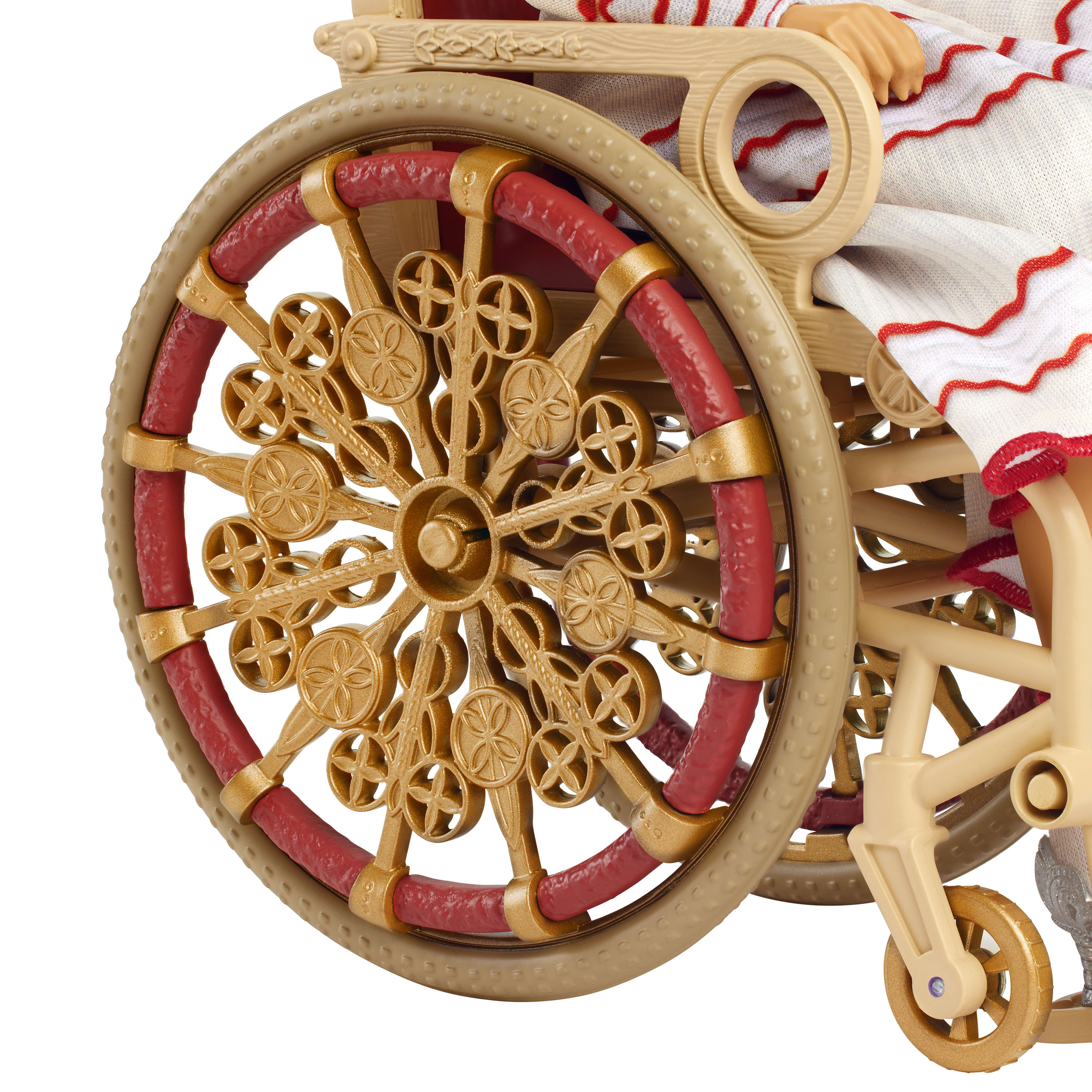 Zbliżenie wózka inwalidzkiego dla lalek, pokazujące szczegóły kół z ozdobnymi złotymi szprychami i czerwonymi oponami.