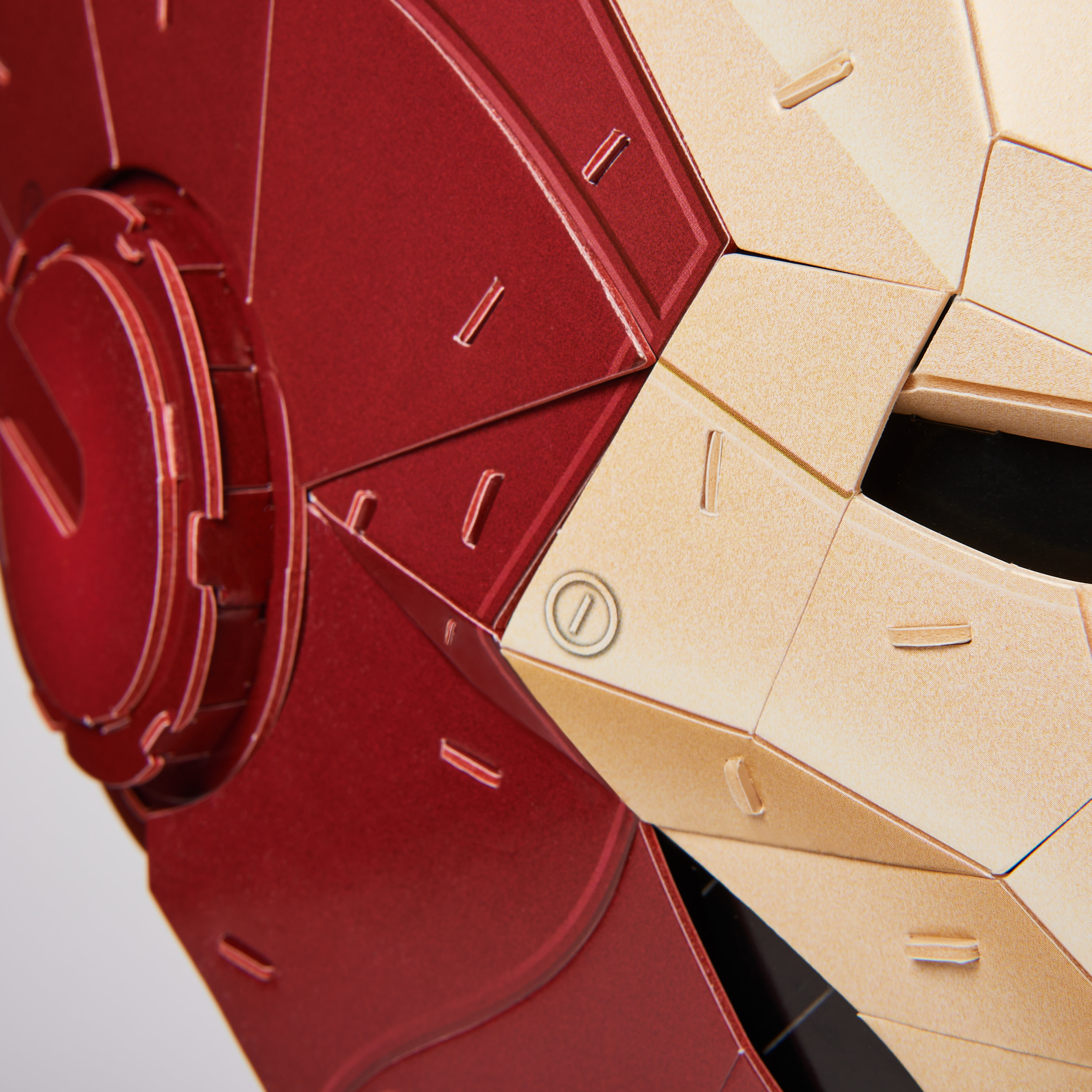 Nahaufnahme eines Iron Man-Helms. Rote und goldene Paneele sind sichtbar. Das Design ist geometrisch und montiert.