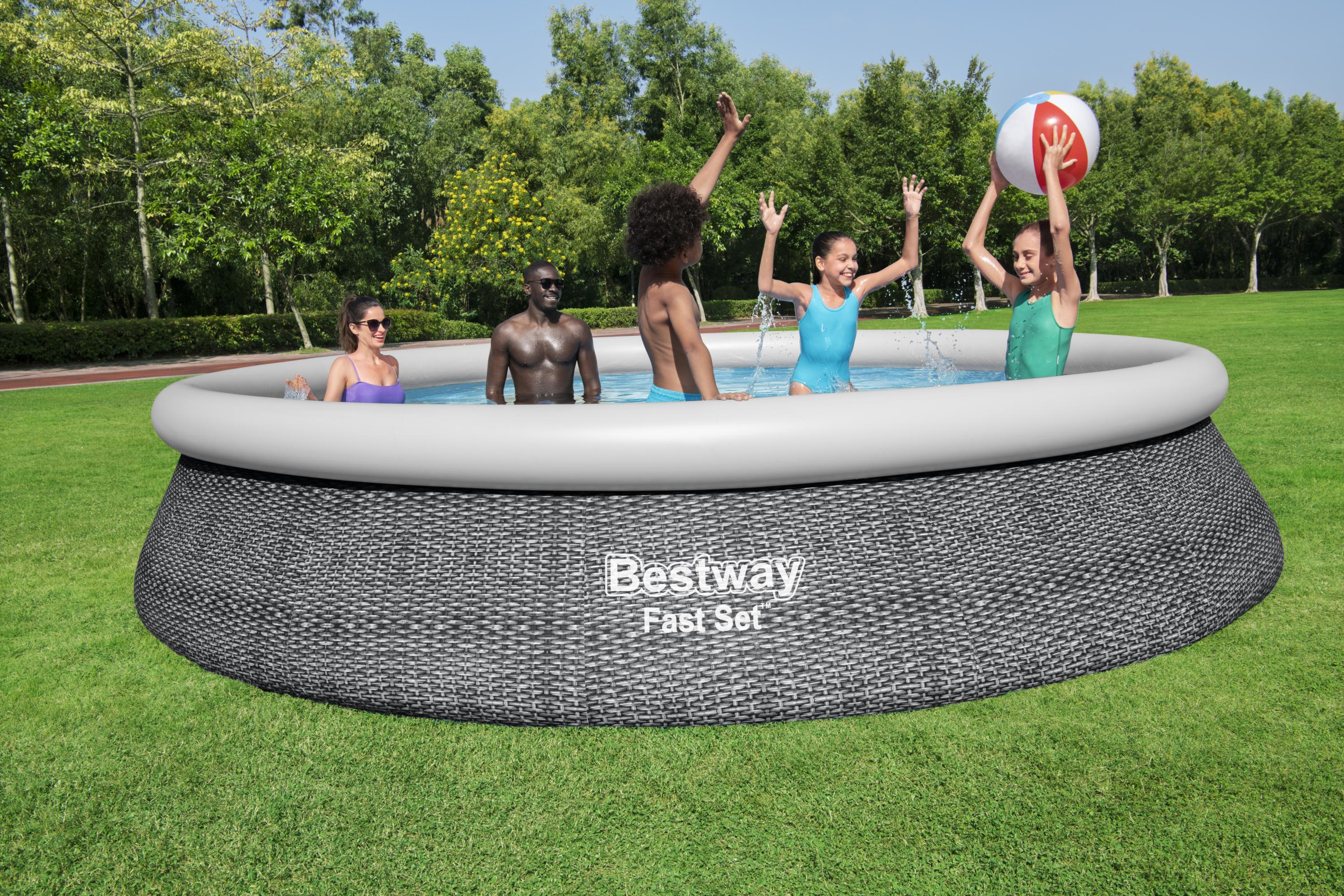 Menschen in einem Pool, einer mit Ball. Grüner Rasen und Bäume im Hintergrund.