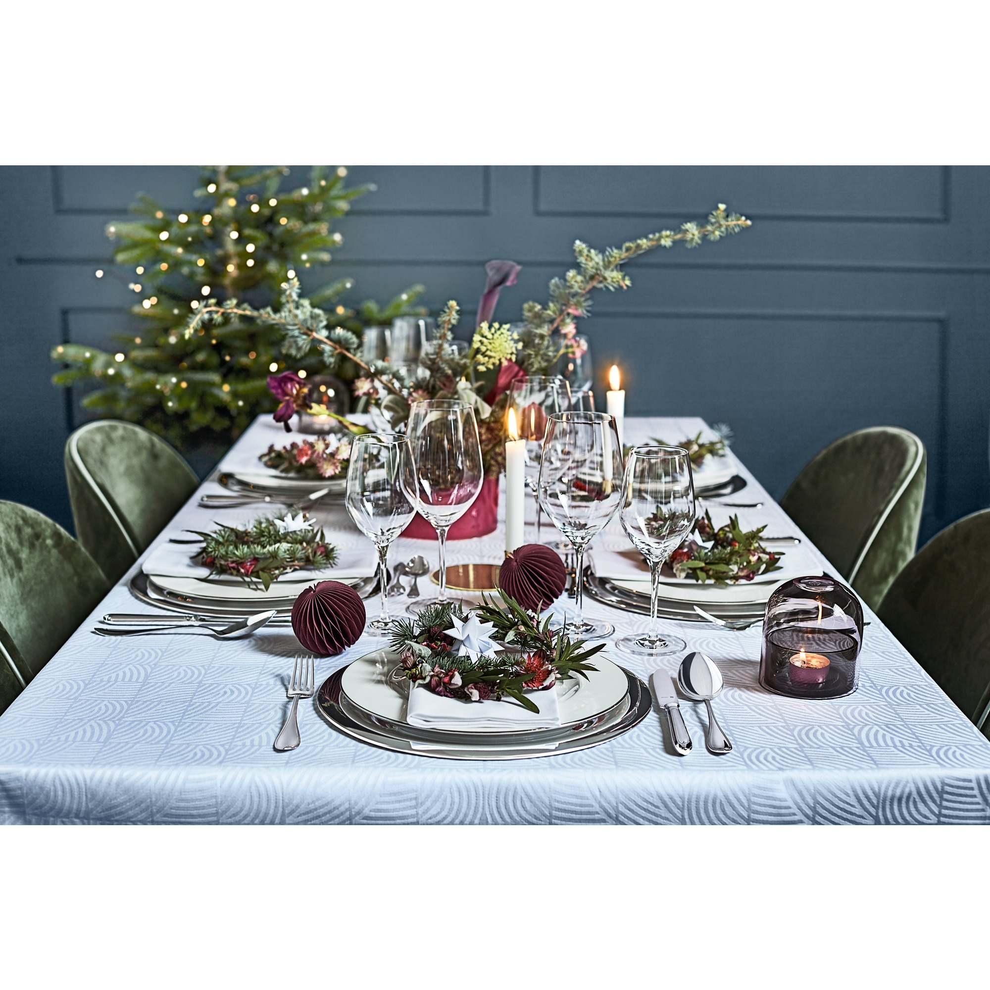 Festliche Tischdekoration mit Weihnachtsbaum, Blumen, Kerzen und elegantem Geschirr.