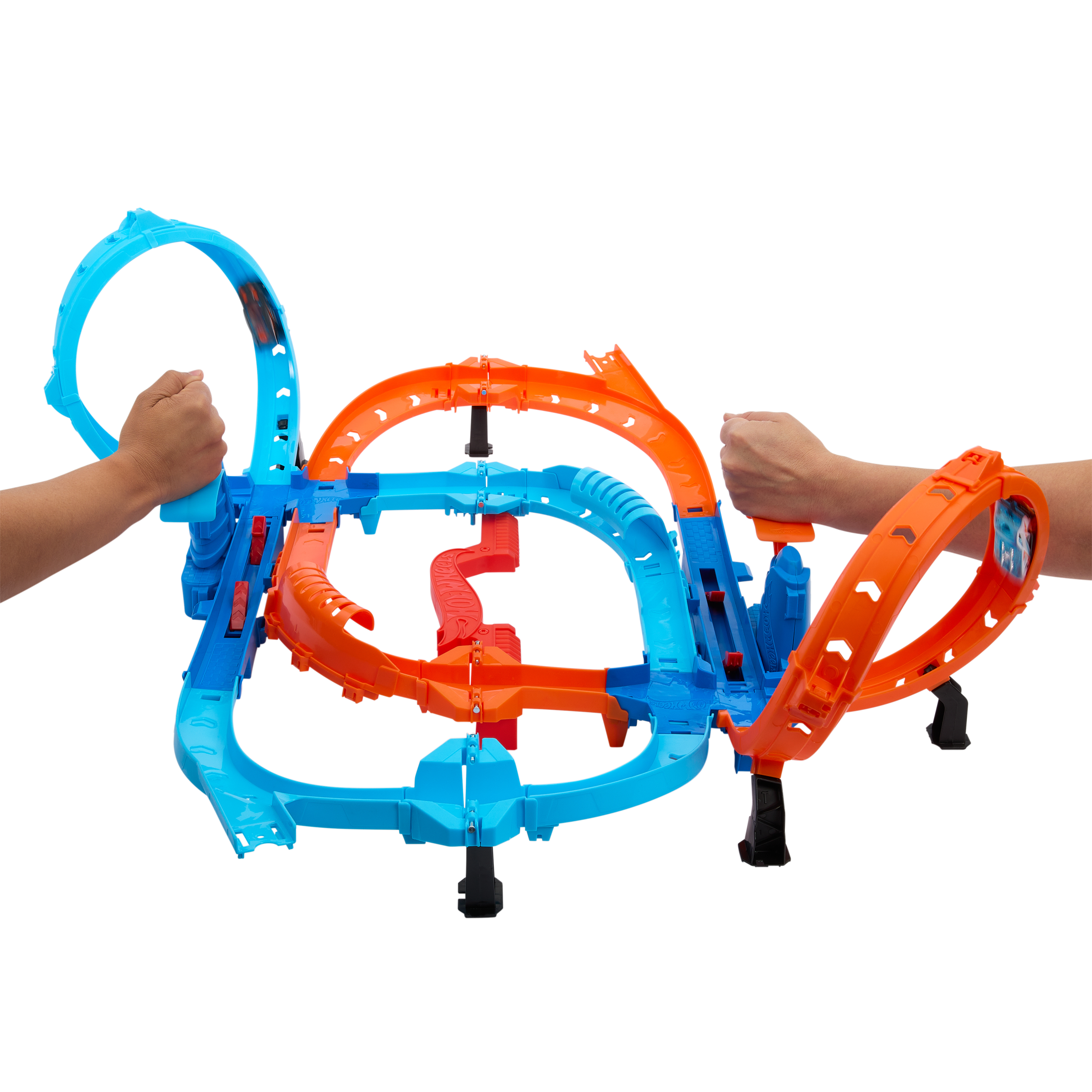 Ein Hot-Wheels-Streckenset mit zwei Händen, die Teile halten. Es ist blau, orange und rot auf weißem Hintergrund.
