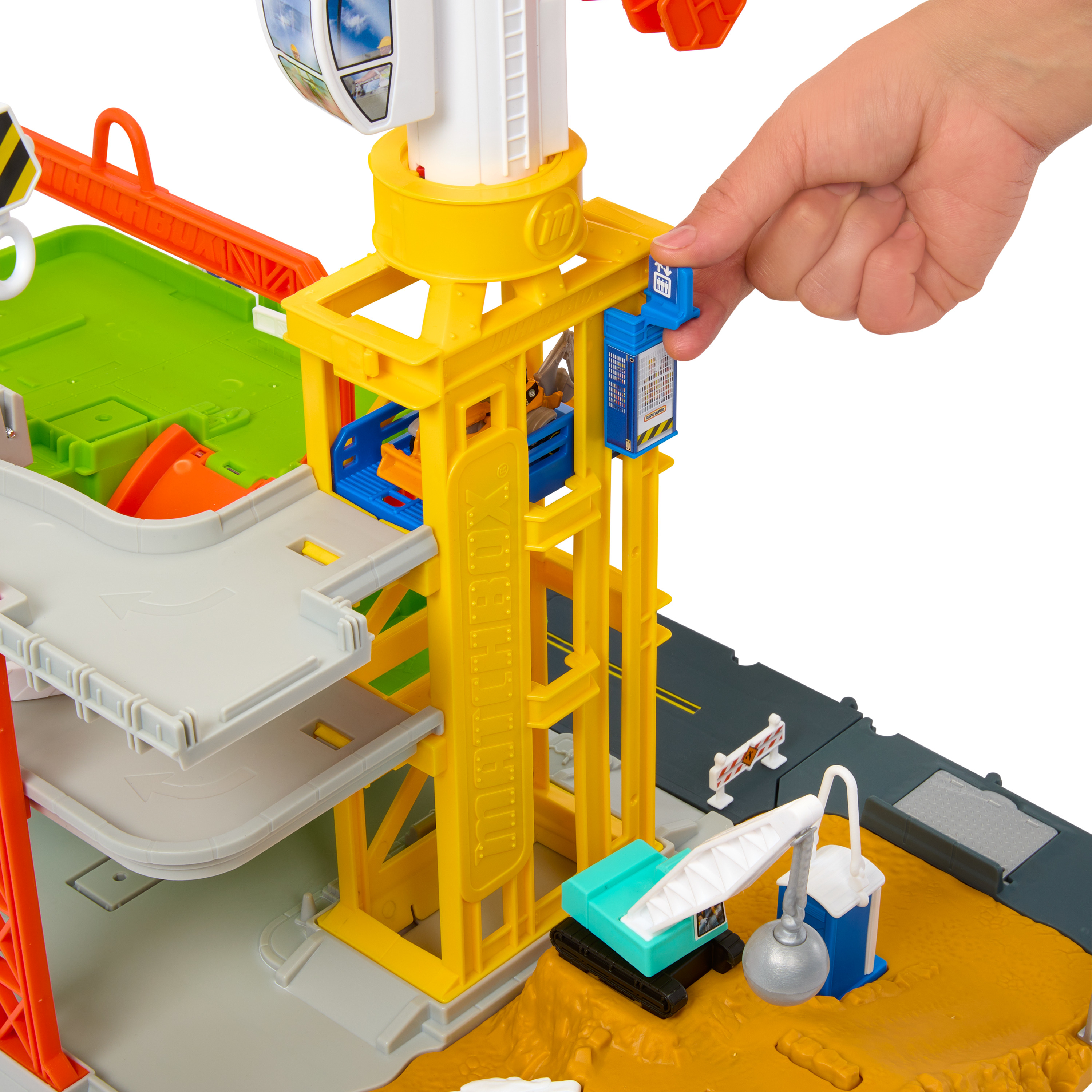 Una mano interactúa con un juego de construcción de juguetes, grúa amarilla, niveles de estacionamiento grises y una pequeña excavadora.