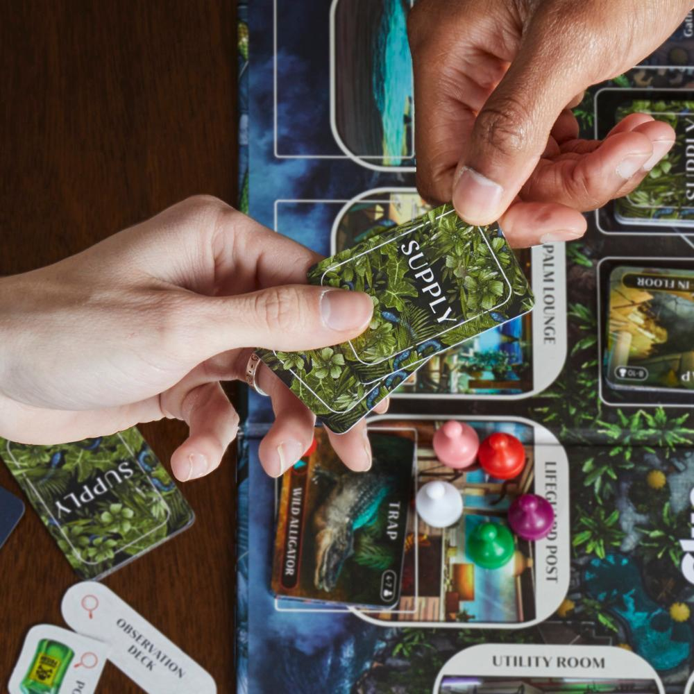 Hände halten Karten über einem Brettspiel. Karten sagen 'Supply' und zeigen Blätter. Andere Karten und Spielsteine sind sichtbar.