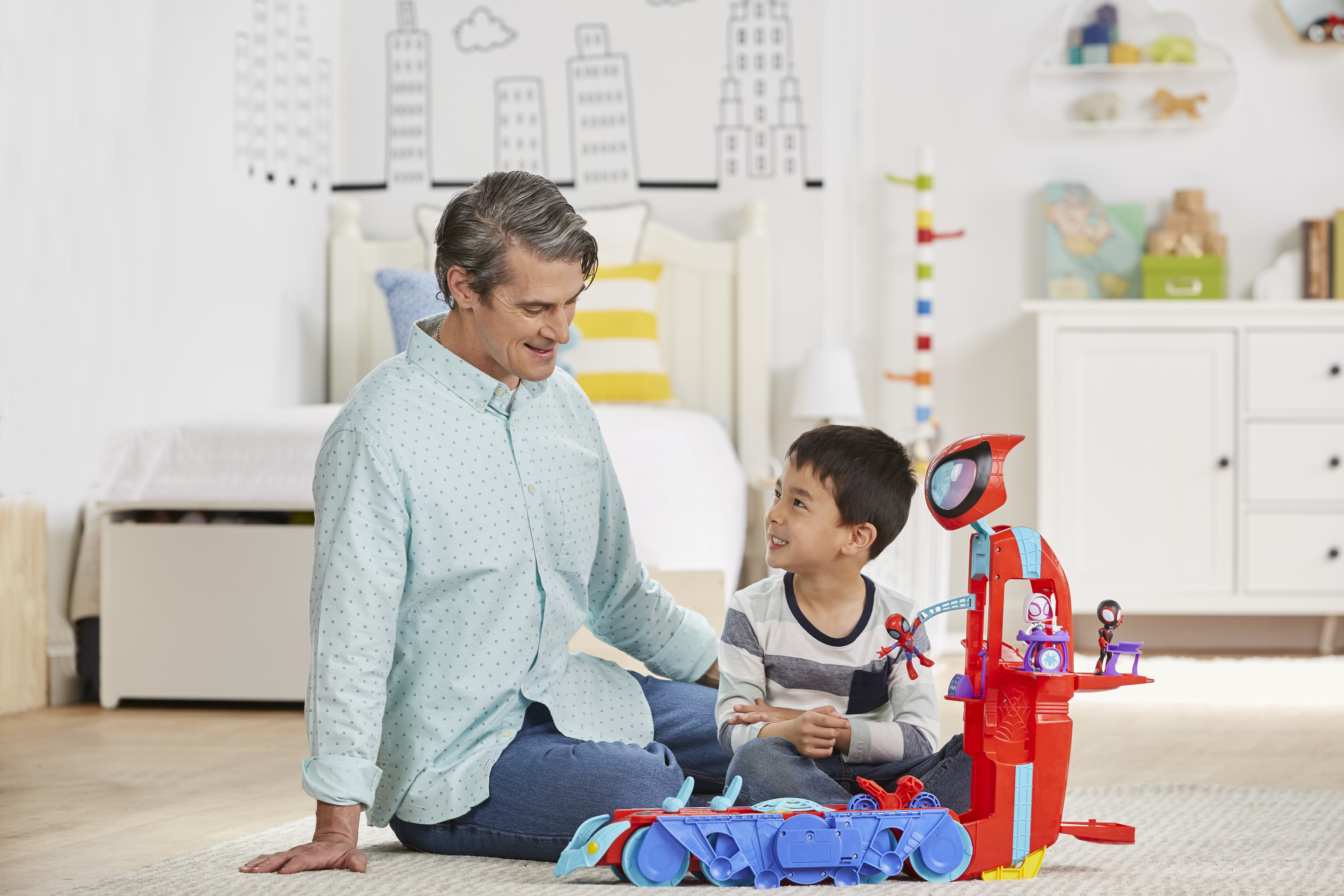 Mężczyzna i chłopiec bawią się zabawką. Zabawka to czerwono-niebieski zestaw Spidermana.