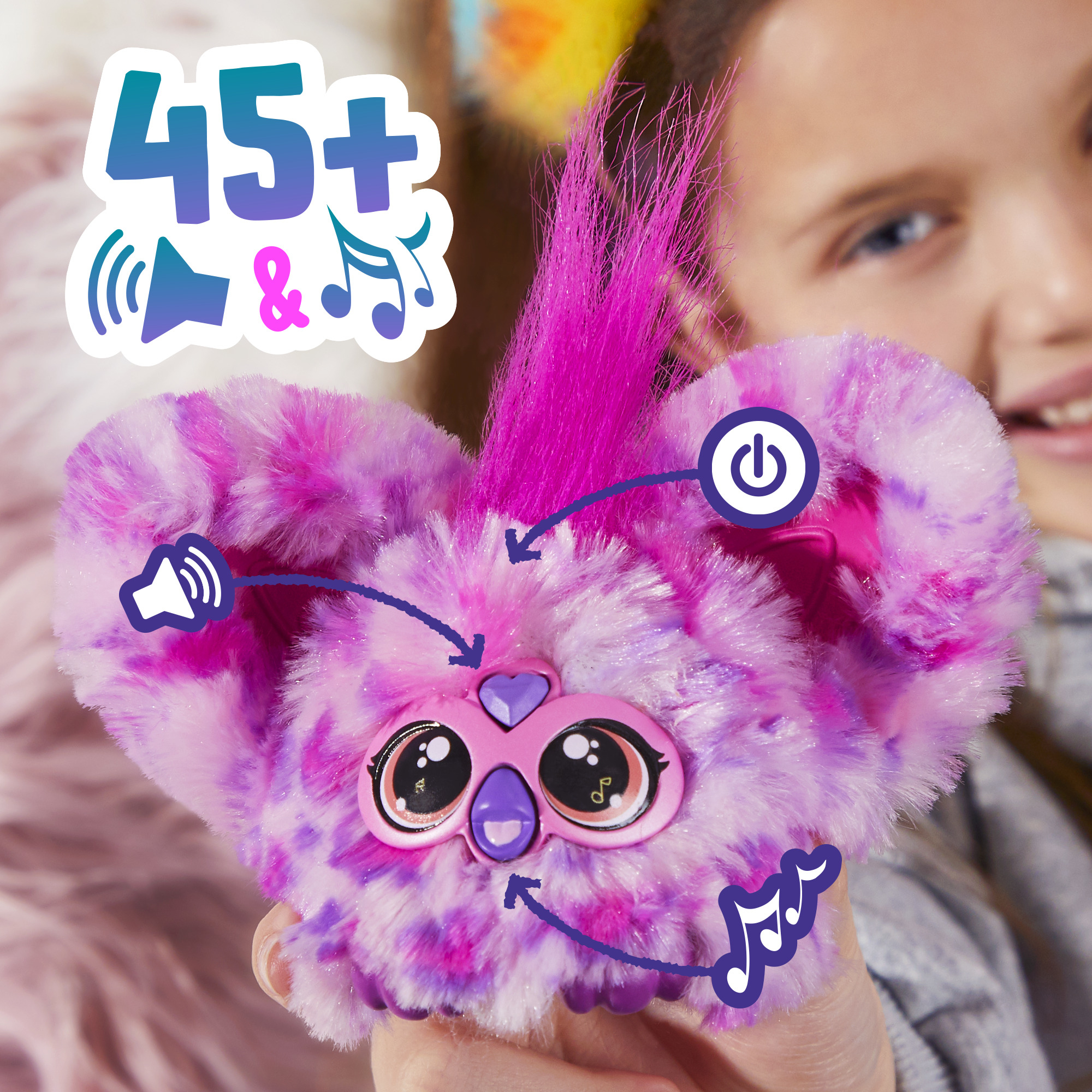 Una niña sostiene un peluche morado con ojos y un botón de encendido. El juguete tiene una pegatina que dice 45+ y notas musicales.