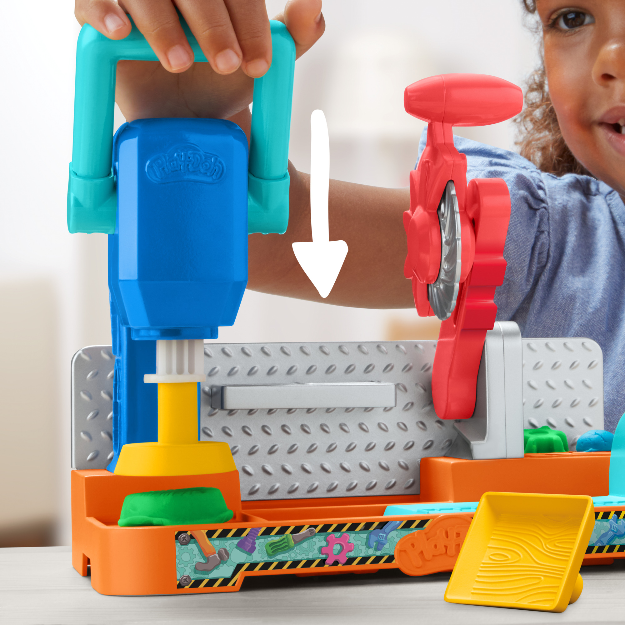 Un niño juega con un juego de Play-Doh. Tiene componentes azules, naranjas y amarillos. Una sierra roja está a la derecha.