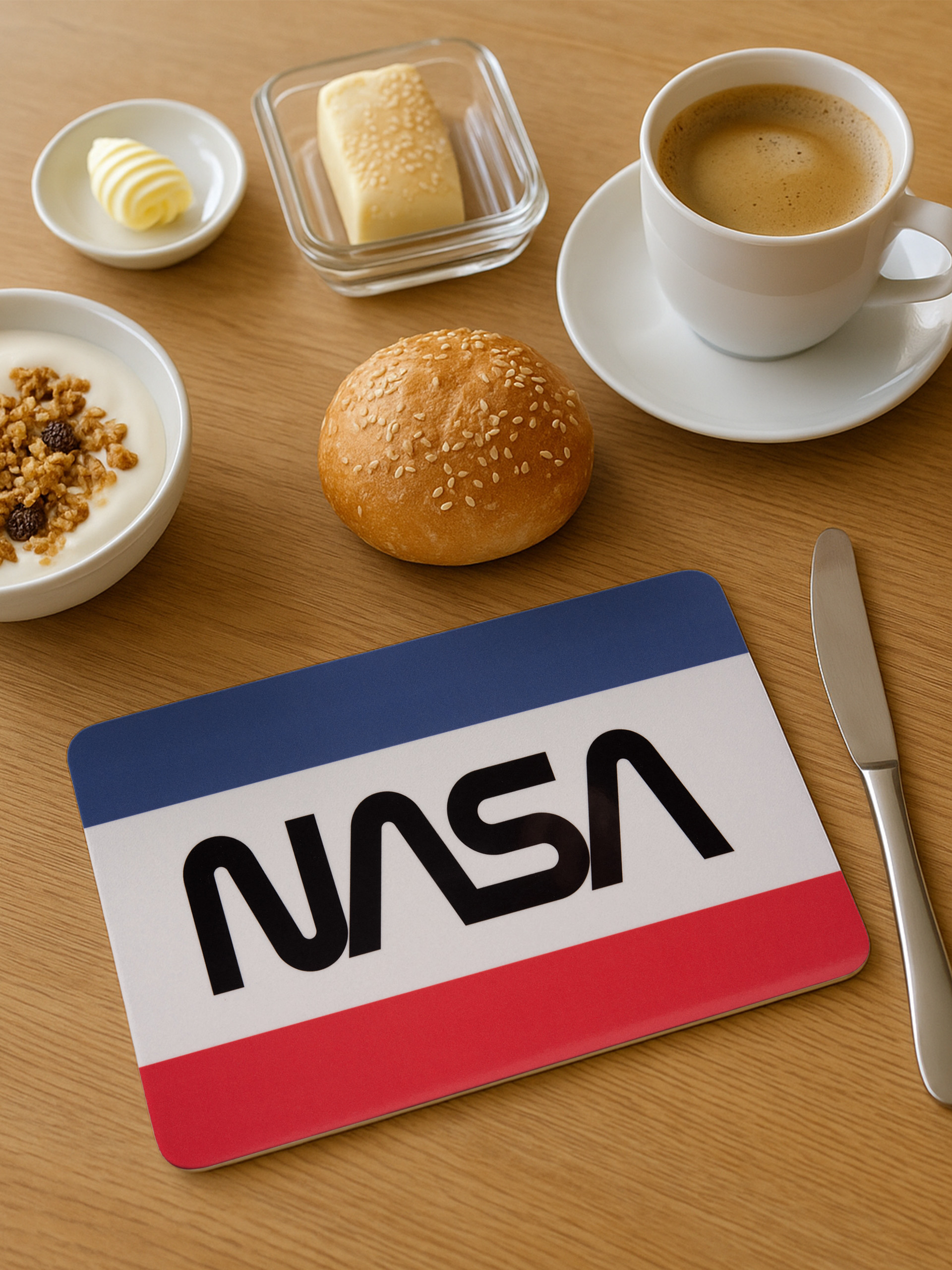 Frühstücksszene: Kaffee, Joghurt, Butter, Brötchen und ein NASA-Artikel auf einem Holztisch.