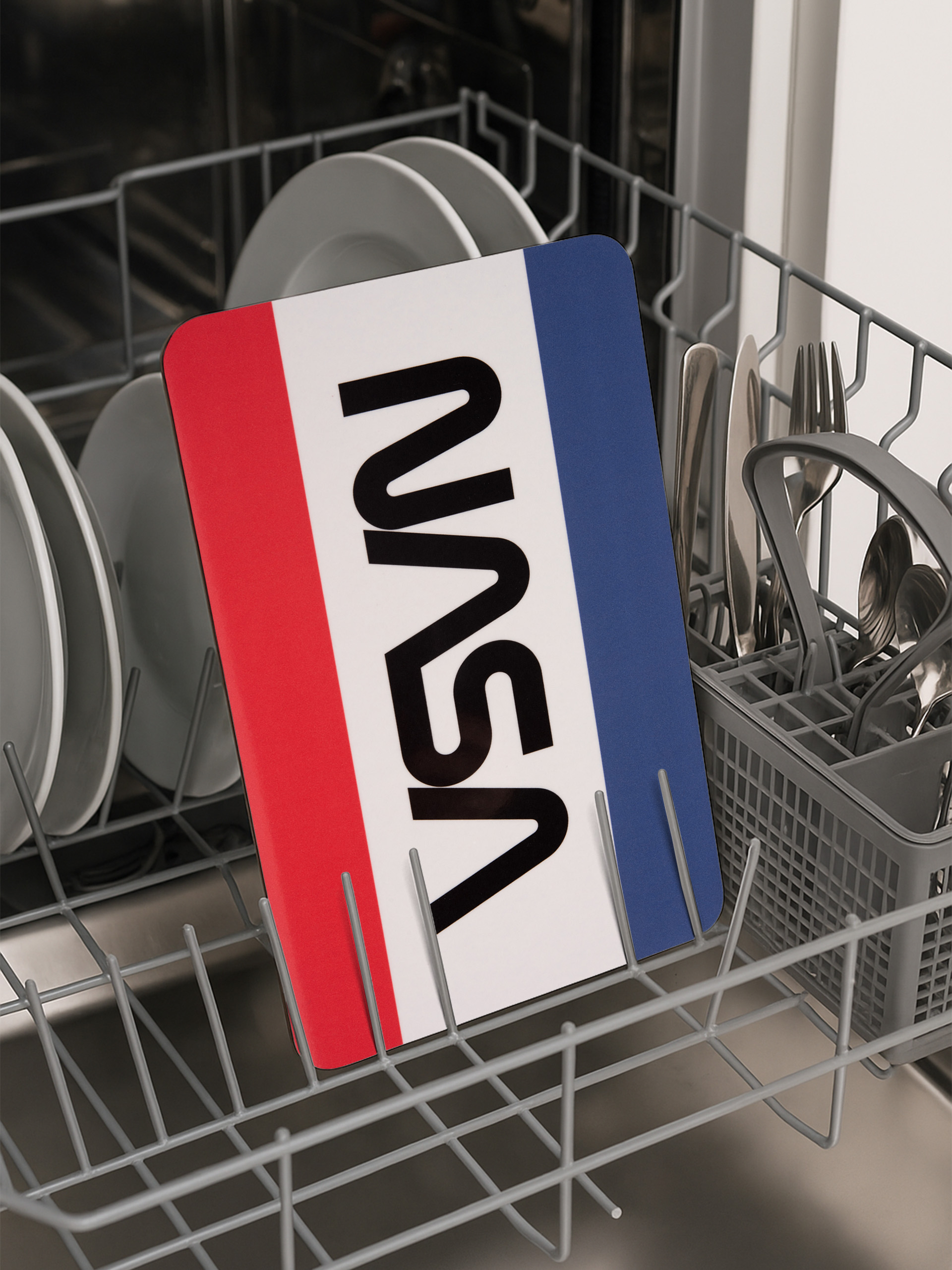 Ein NASA-Schild in einer Spülmaschine. Das Schild hat ein rot-weiß-blaues Design. Geschirr und Besteck sind ebenfalls sichtbar.