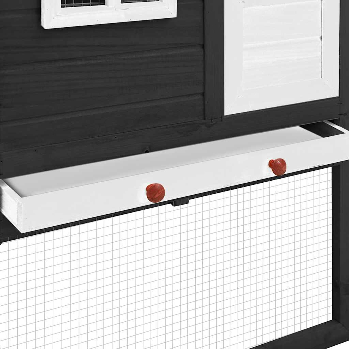 Nahaufnahme eines Hühnerstalls mit weißem Tablett mit roten Knöpfen, dunklem Holz, weißem Fensterladen und Drahtgeflecht.