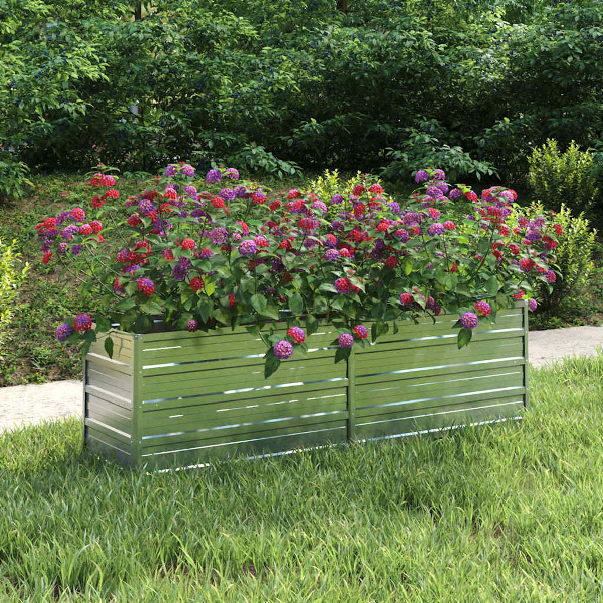 Eine Metallpflanzkasten mit roten und lila Blumen steht auf Gras. Bäume bilden den Hintergrund der Szene.