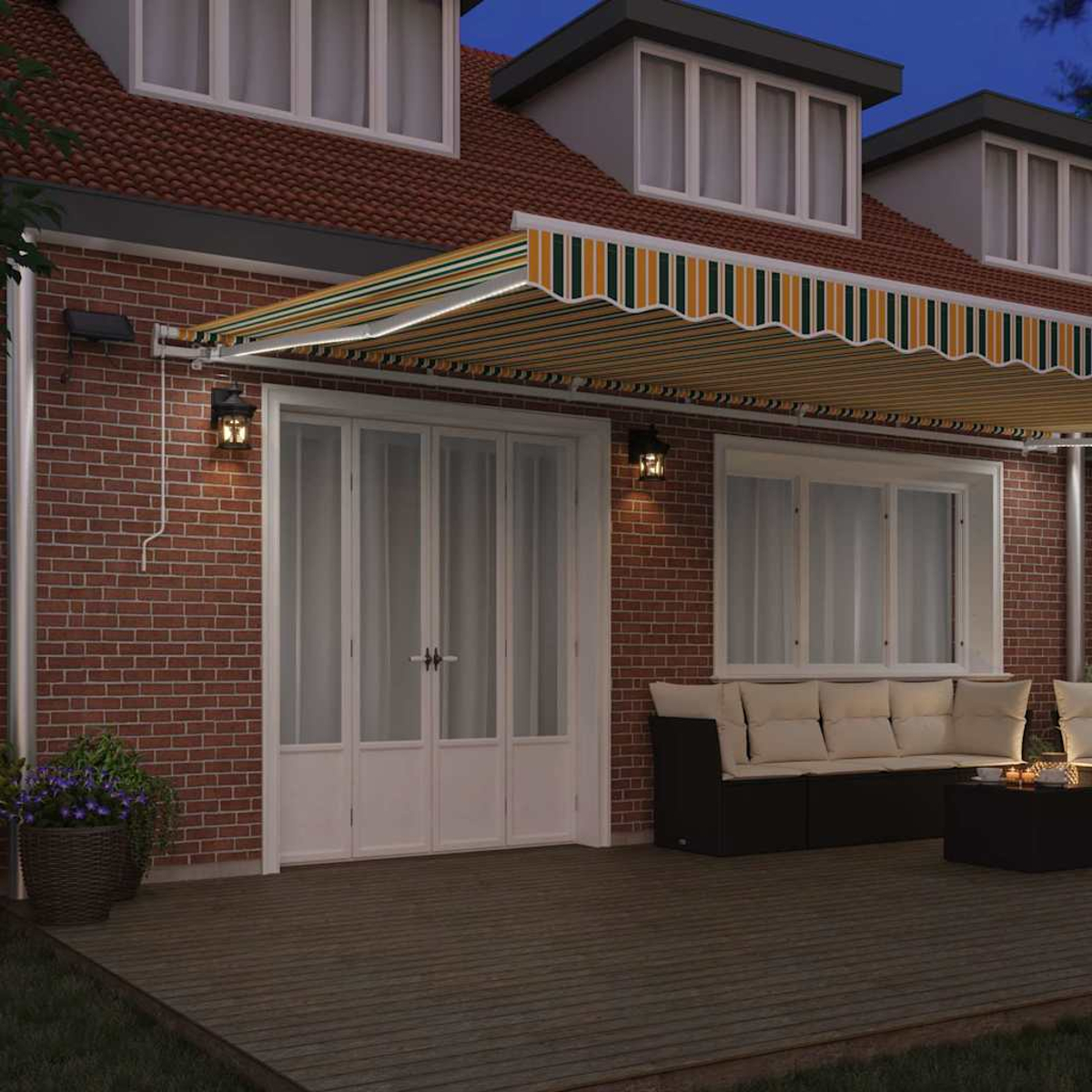 Ein Haus mit gestreifter Markise, Backsteinmauern und Holzterrasse. Auf der Terrasse stehen eine Couch und ein Tisch. Nachthimmel.